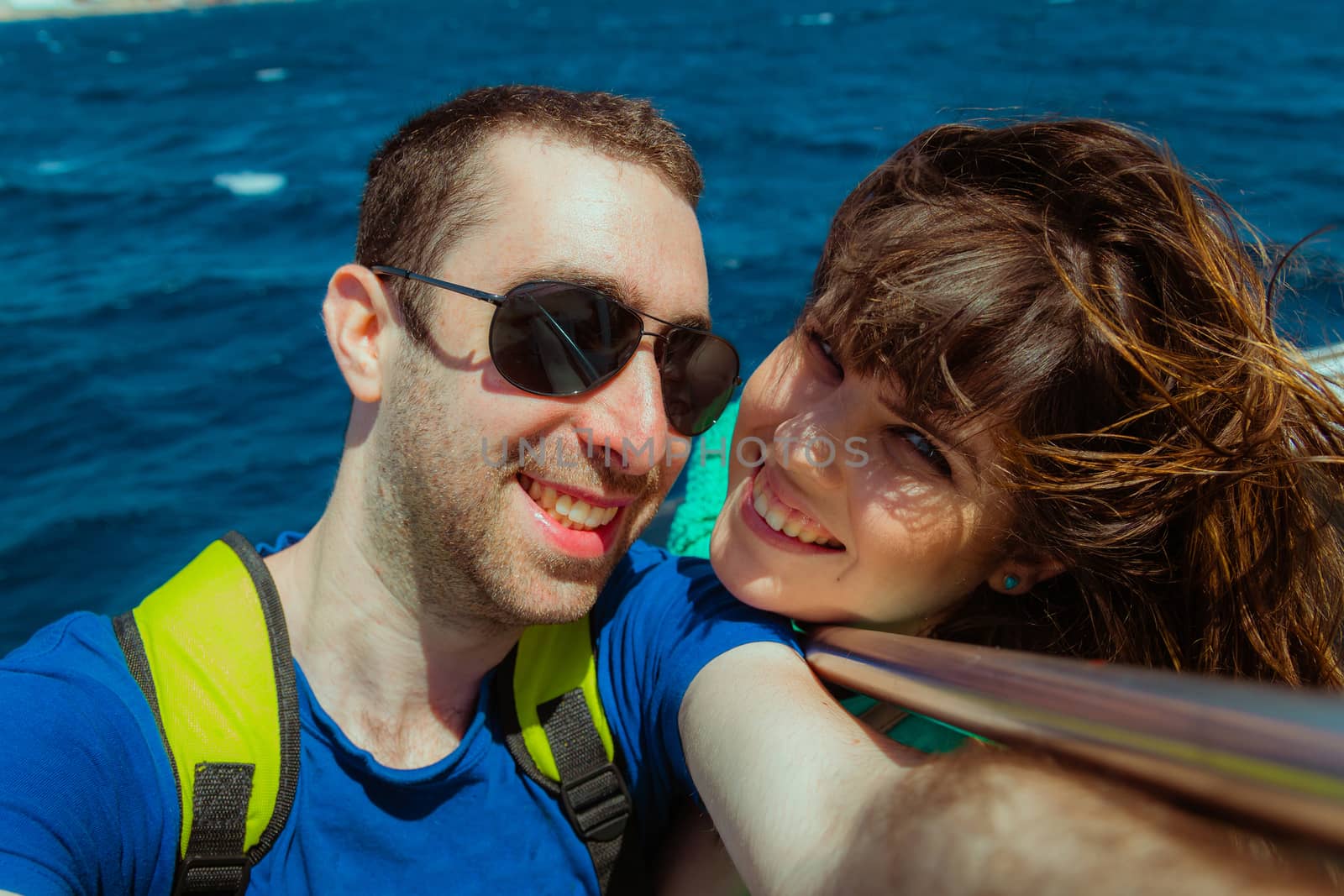Happy couple sailing on a boat and taking selfie with smartphone or camera.