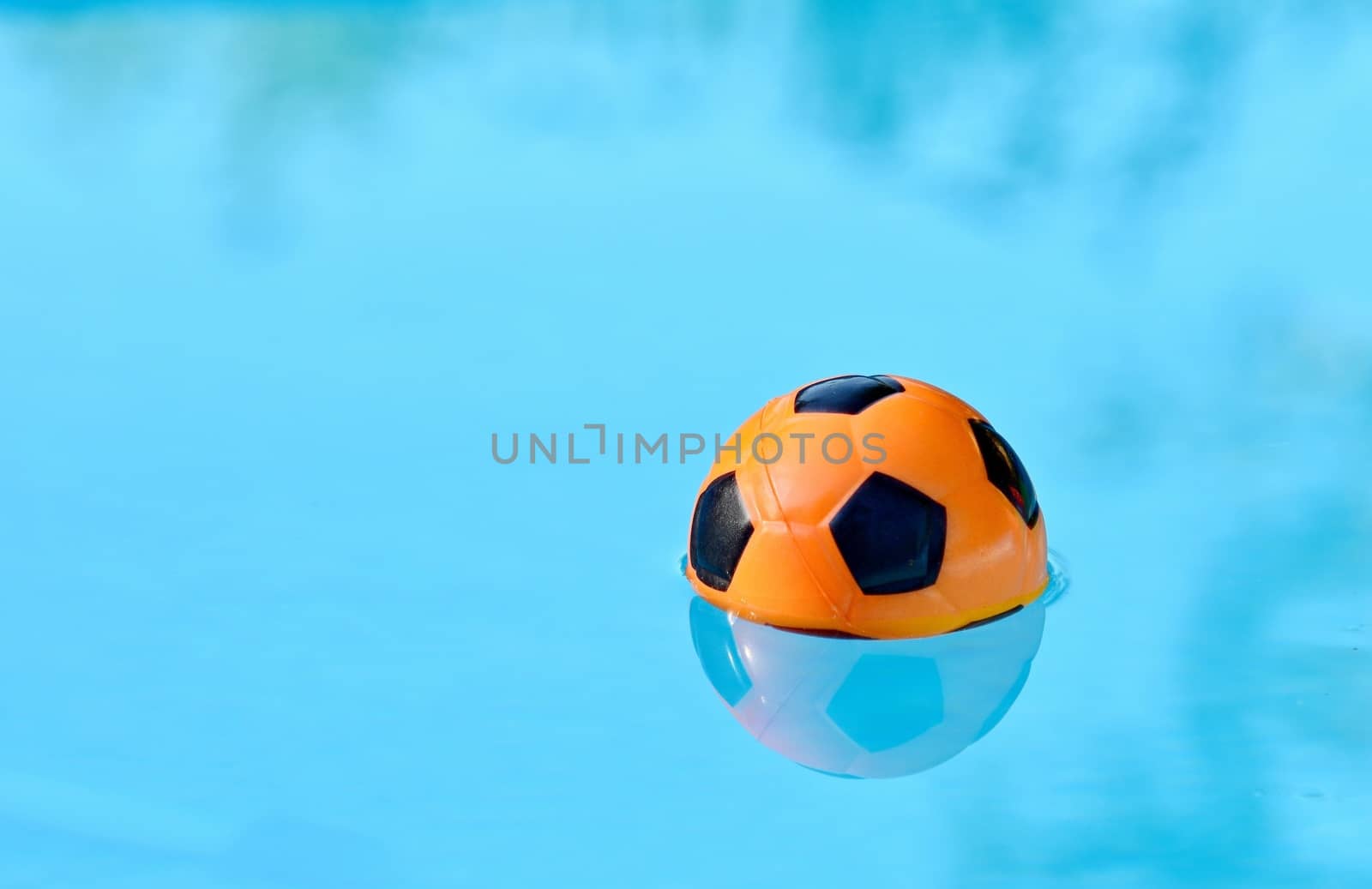 Children playing ball floating in swimming pool.