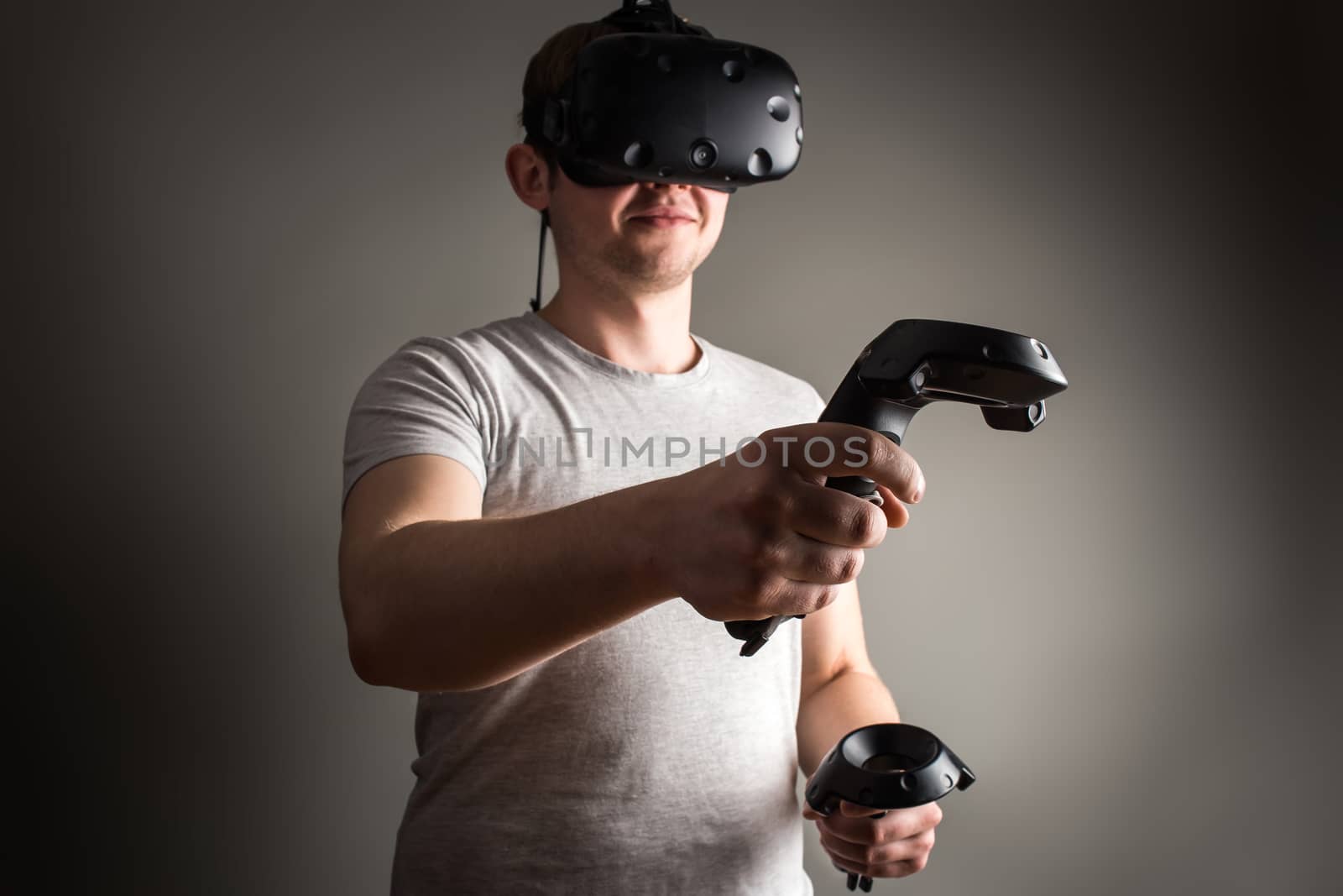 technology, gaming, entertainment and people concept - happy young man with virtual reality headset or 3d glasses with controller gamepad playing racing video game at home