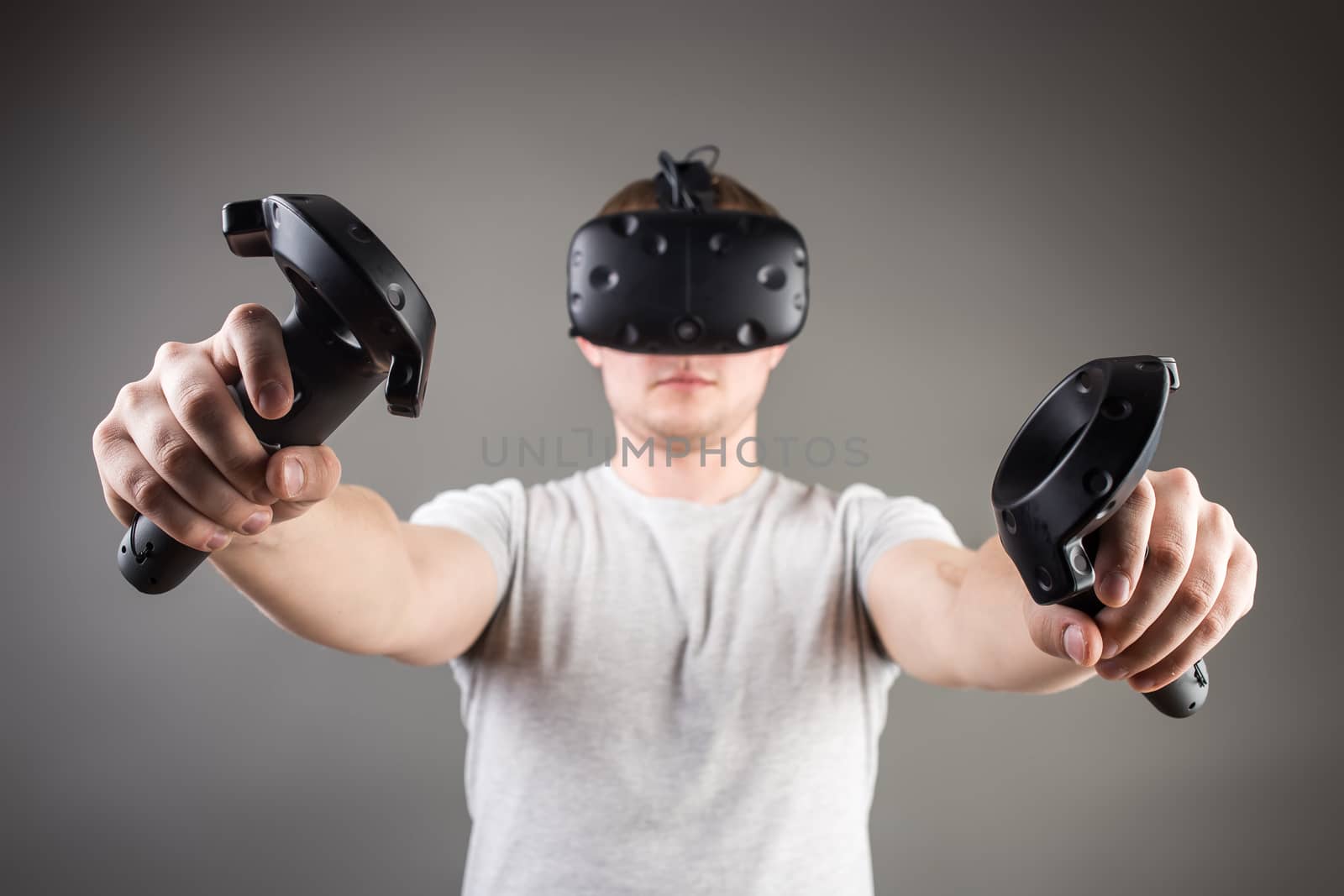 technology, gaming, entertainment and people concept - happy young man with virtual reality headset or 3d glasses with controller gamepad playing racing video game at home