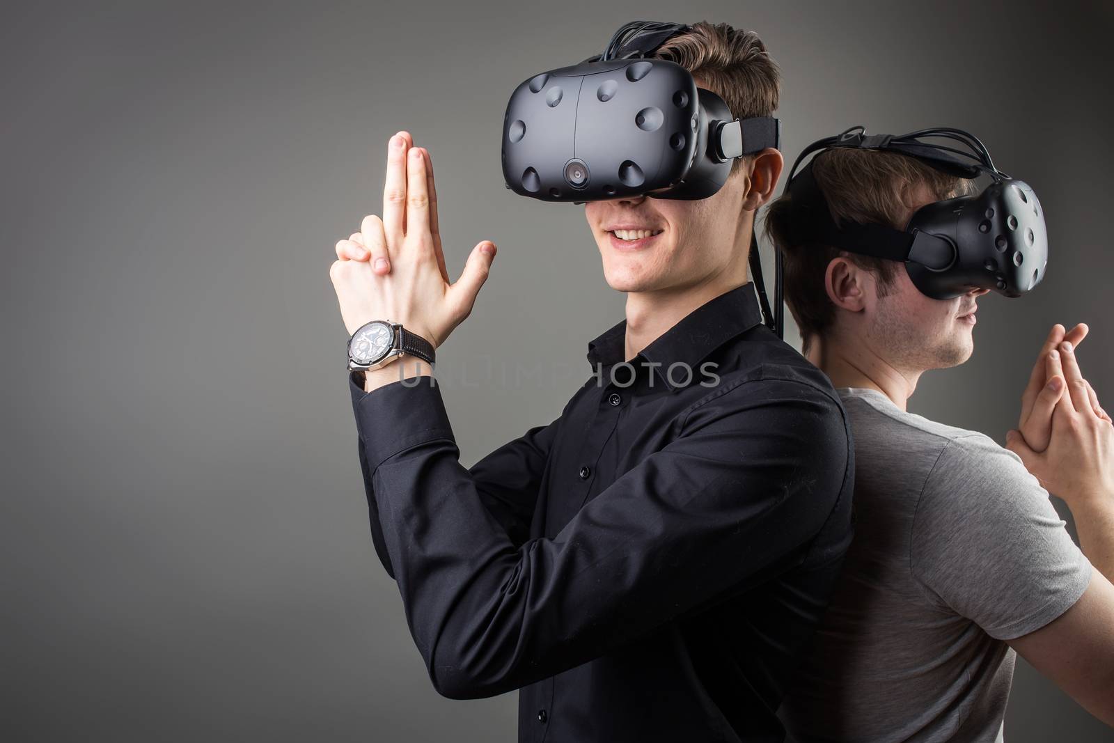 Shot of two young man standing with VR goggles and keep joysticks or finger as a gun