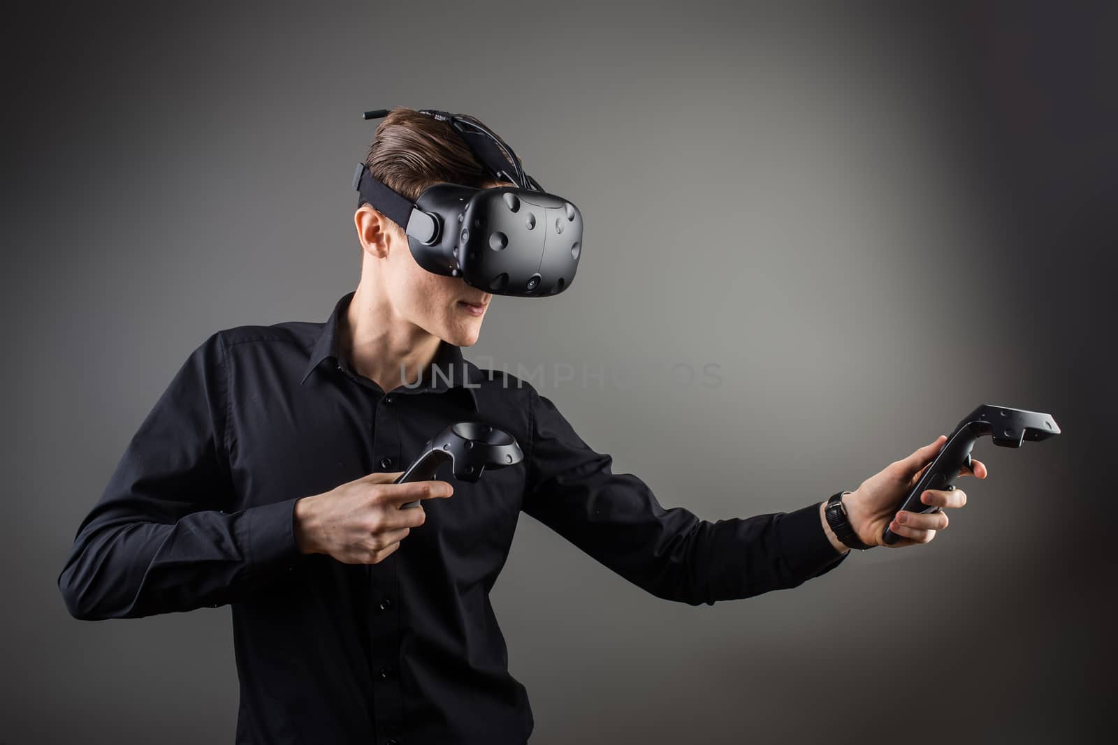 attractive man wearing virtual reality headset with two handheld trackpads or controllers by ufabizphoto