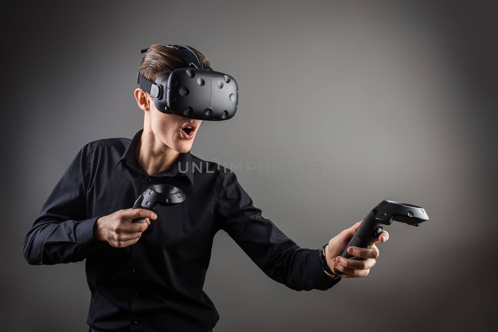 technology, gaming, entertainment and people concept - happy young man with virtual reality headset or 3d glasses with controller gamepad playing racing video game by ufabizphoto