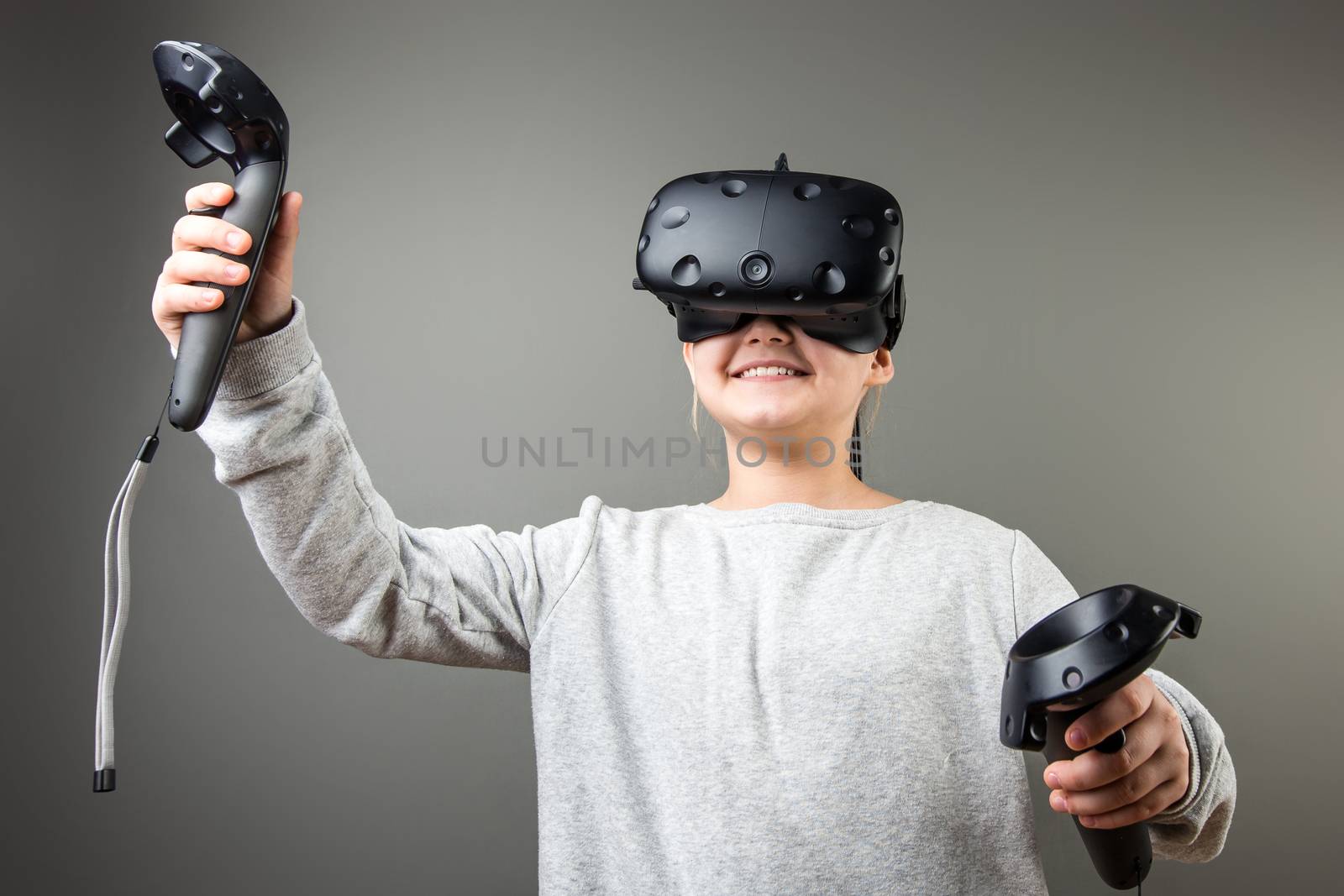 happy Cute little child girl playing game in virtual reality glasses and two joysticks by ufabizphoto