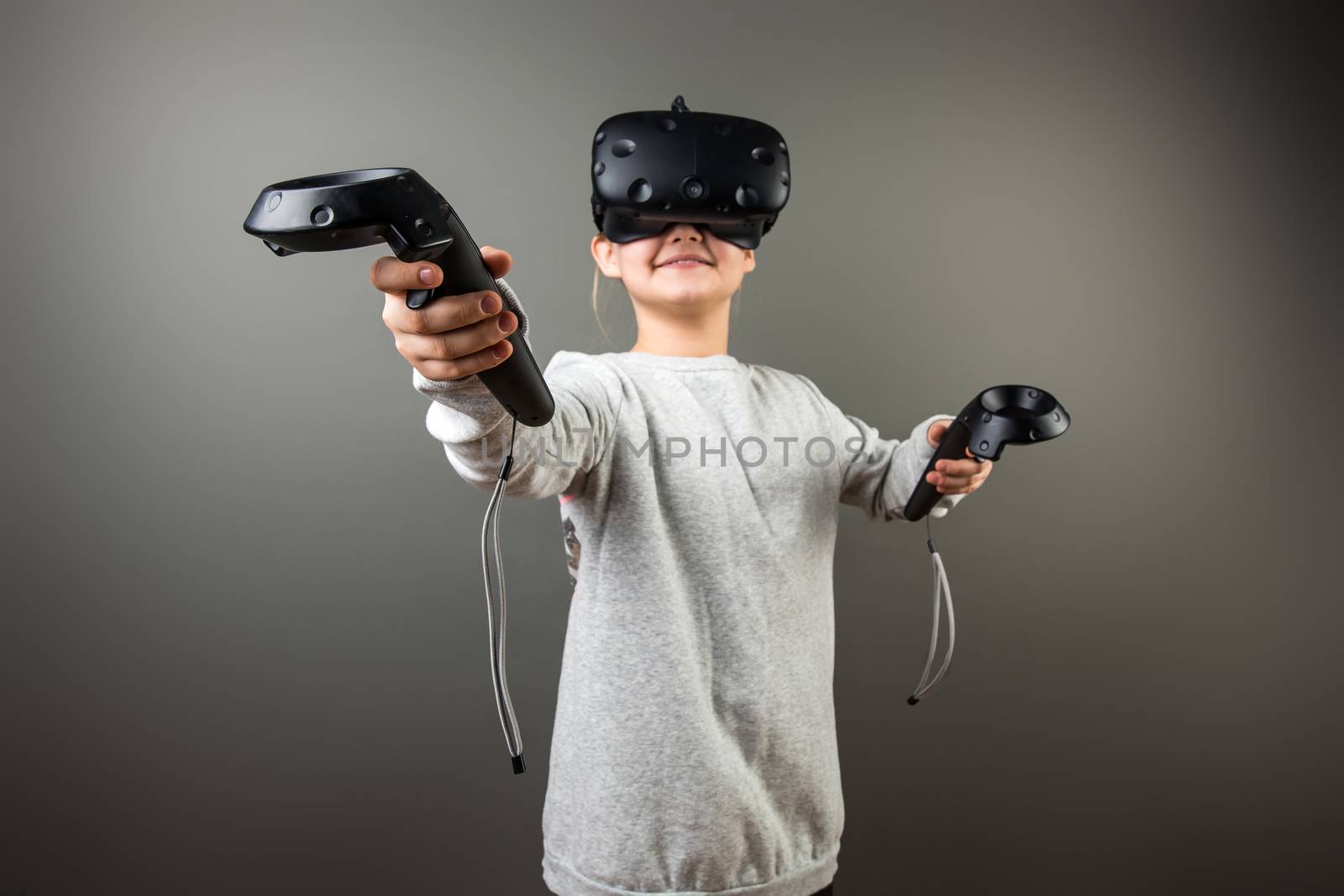 smile Child with virtual reality headset and joystick playing video games by ufabizphoto