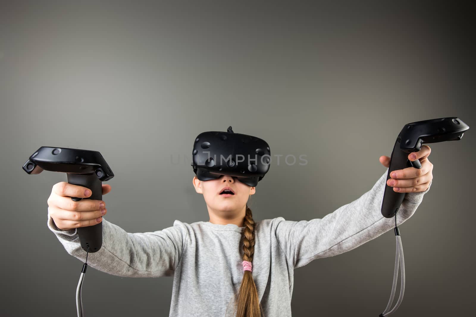 surprised Cute little child girl playing game in virtual reality glasses and two joysticks by ufabizphoto