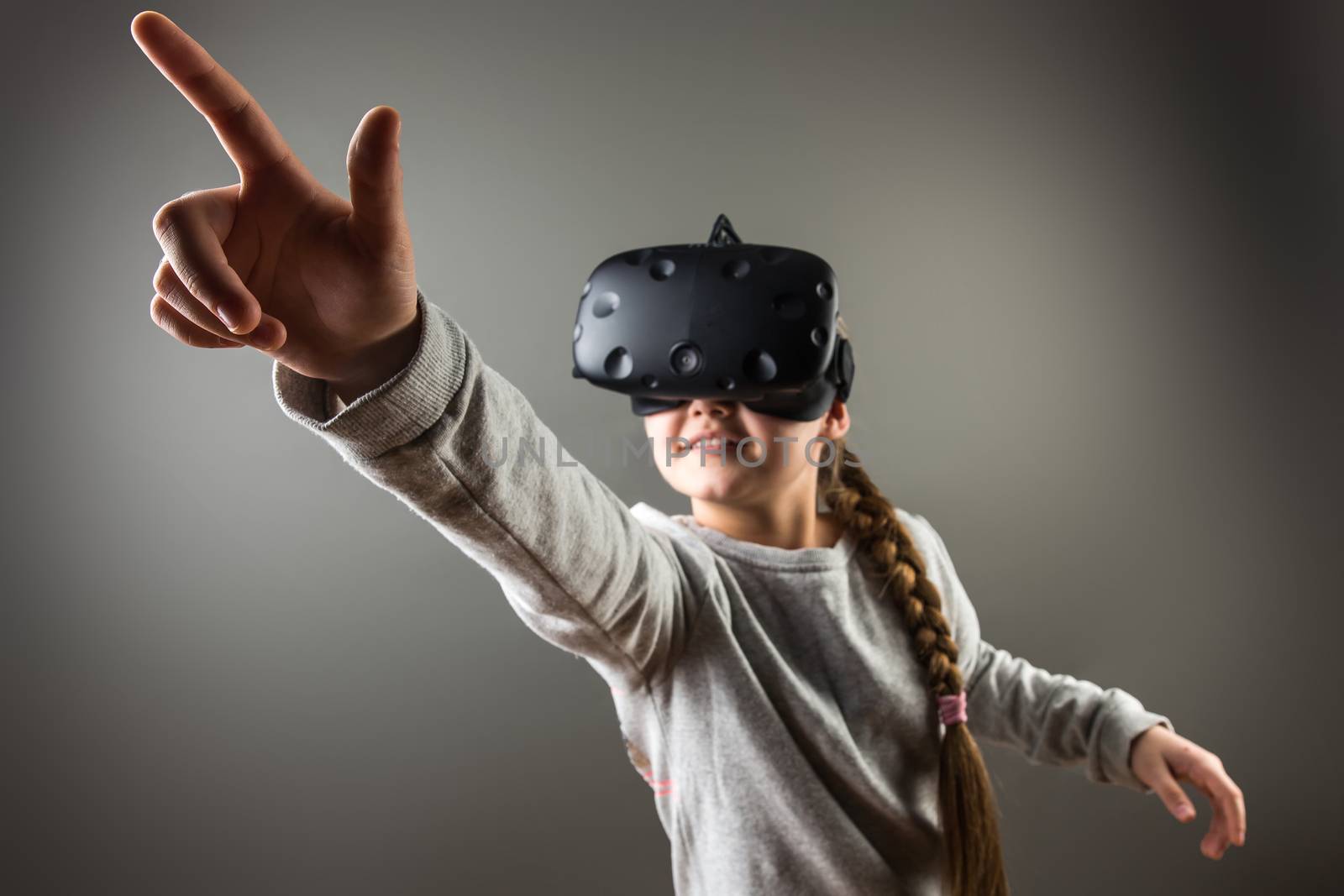girl wearing virtual reality goggles standing on grey background. VR glasses. 360 degrees. Virtual reality headset. VR game. Wearing virtual reality goggles. Smartphone with VR. Virtual reality video. by ufabizphoto