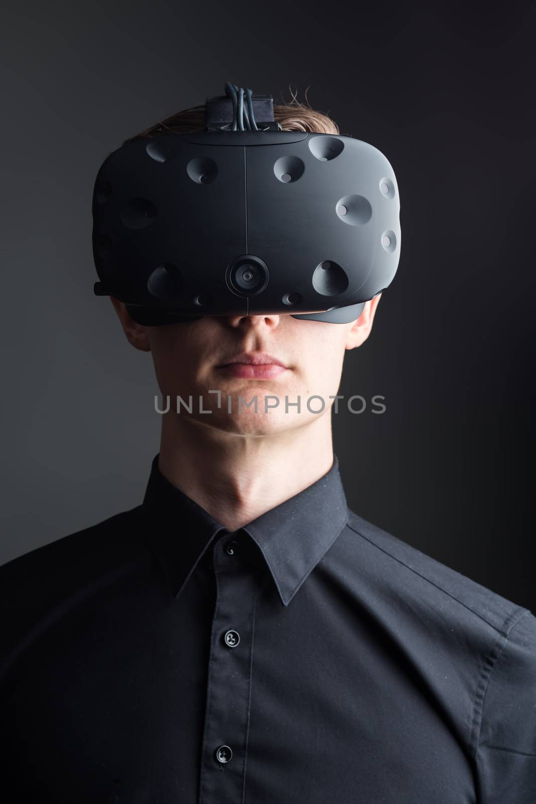 Man wearing virtual reality goggles. Studio shot, gray backgroun