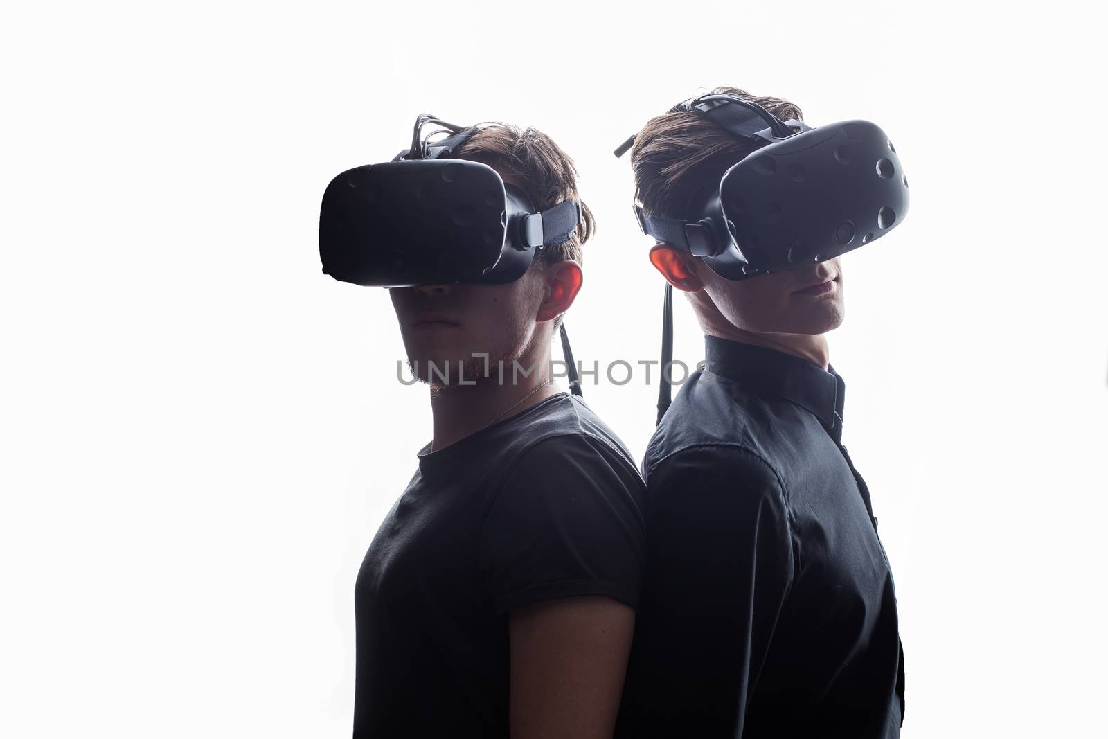 Shot of two young man standing back to back with VR goggles by ufabizphoto