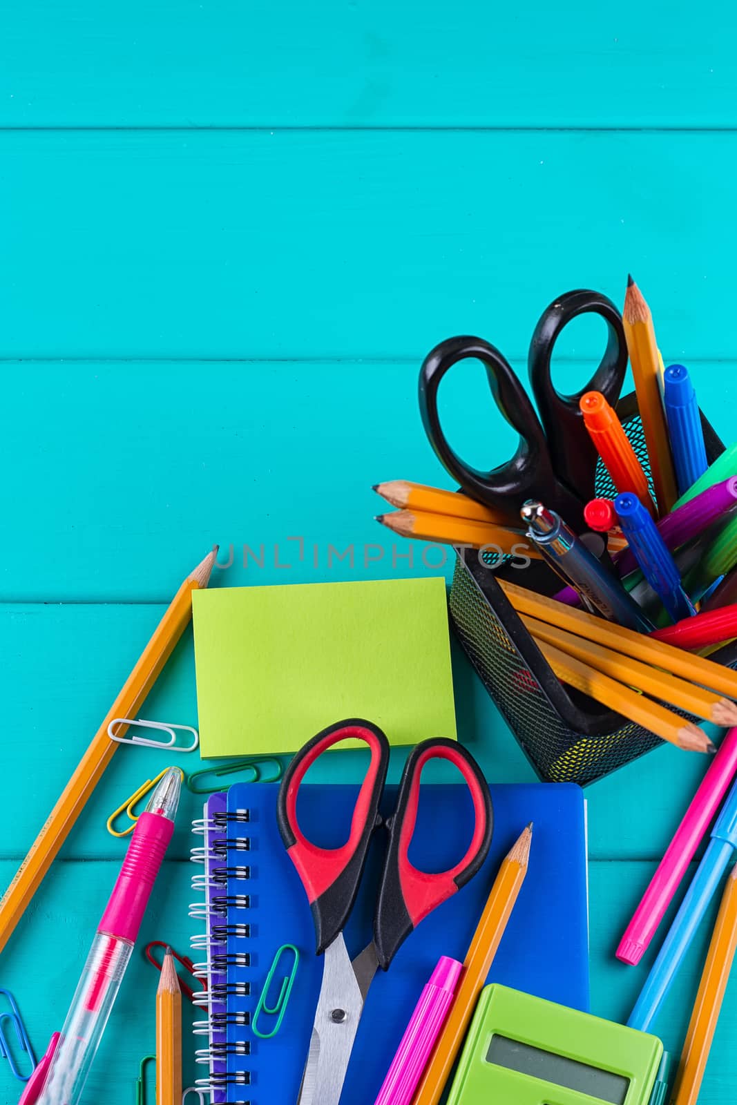 school and office supplies. school background. colored pencils, pen, pains, paper for school and student education on blue wood background. top view