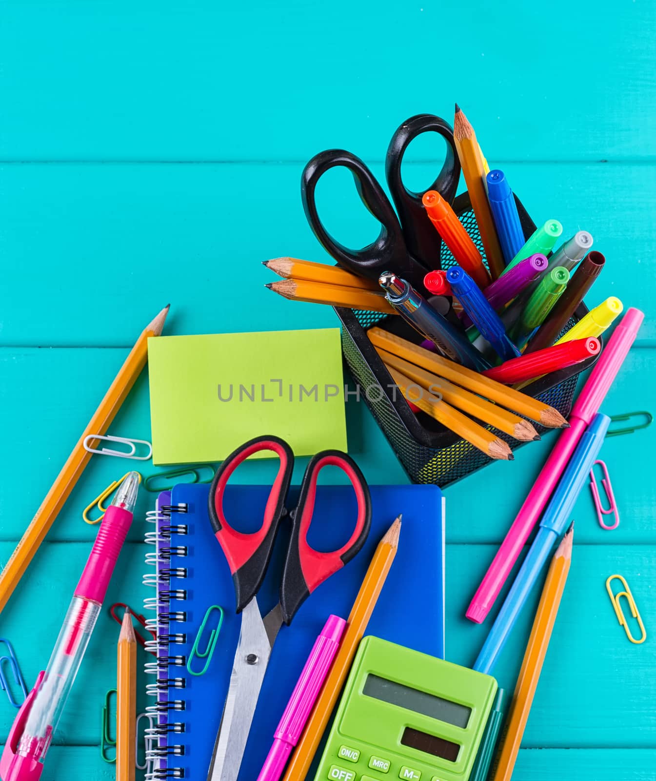 school and office supplies. school background. colored pencils, pen, pains, paper for school and student education on blue wood background. top view