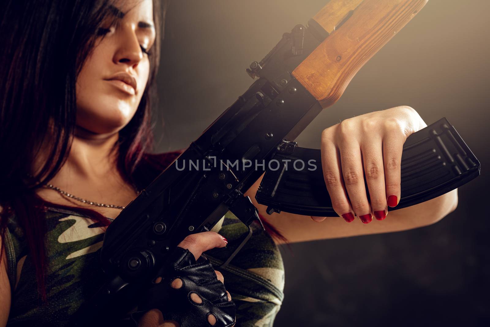 Close-up cleavage woman in camouflage shirt with an automatic rifle in her hand.