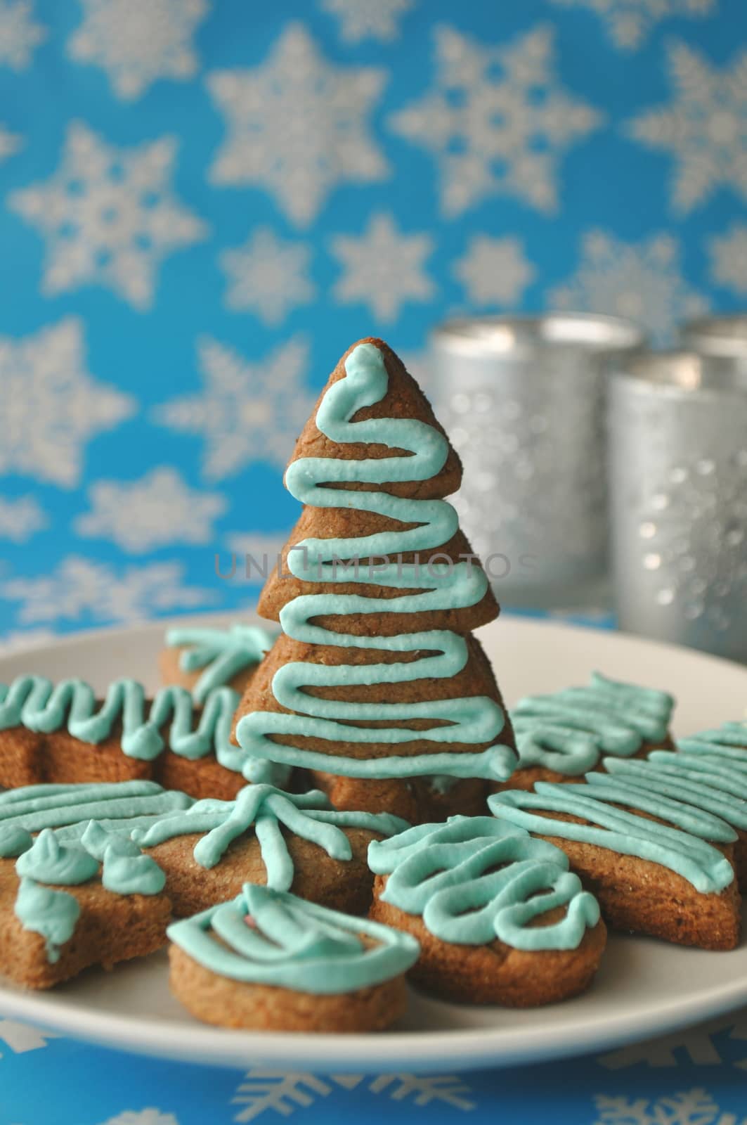 Decorated Christmas honey cookies on winter background with snowflakes and silver tealights