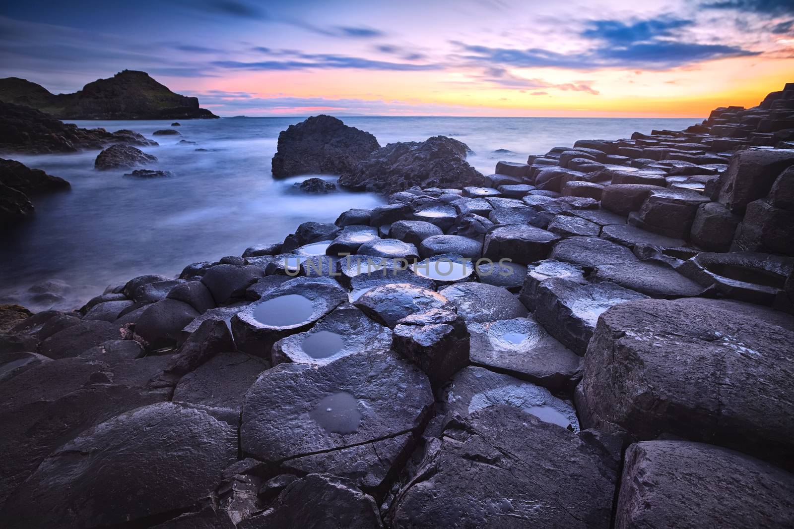 sunset over basalt rocks formation Giant's Causeway, Port Ganny Bay and Great Stookan, County Antrim, Northern Ireland, UK