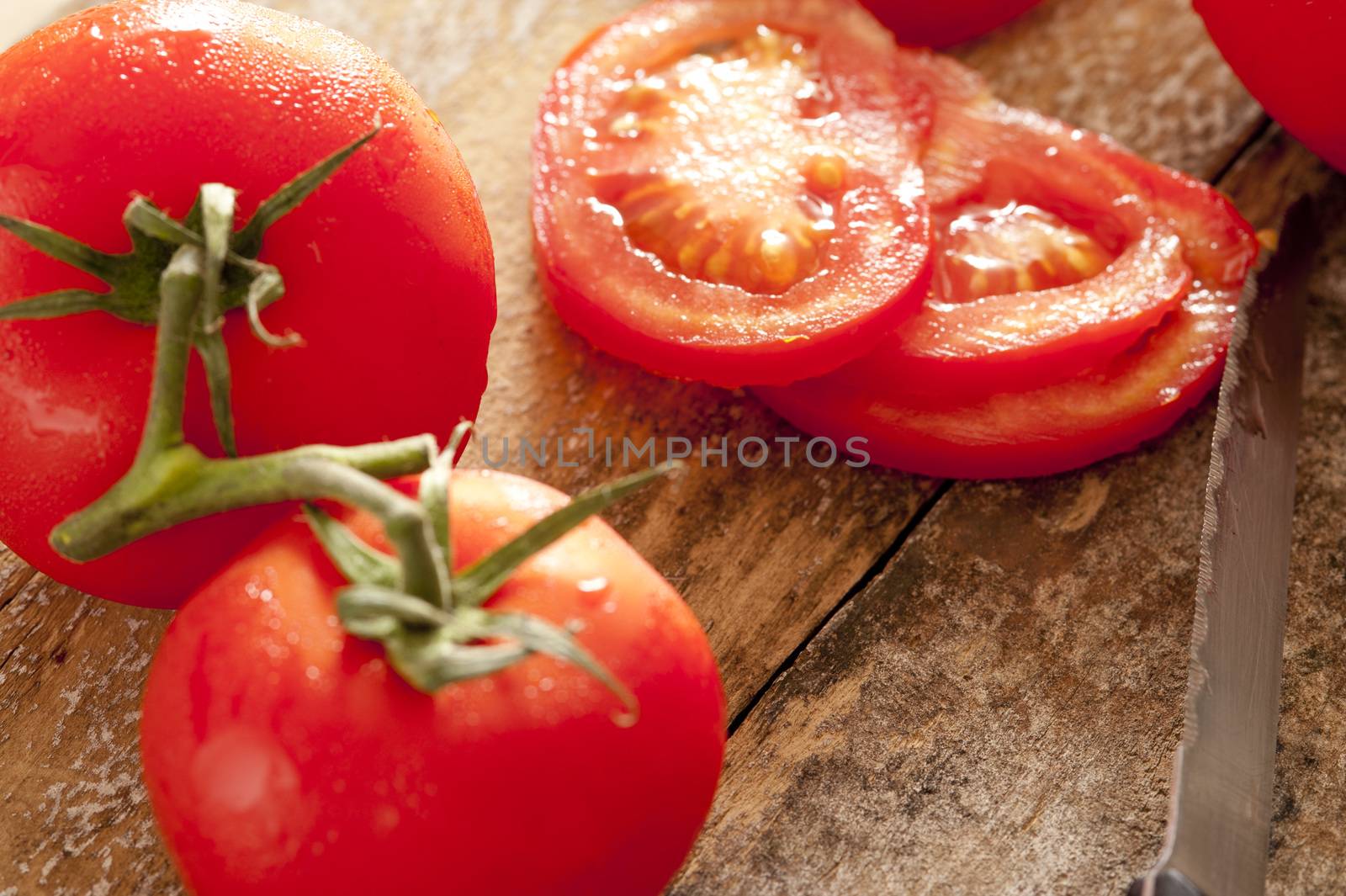 Whole and sliced tomatoes on the vine by stockarch
