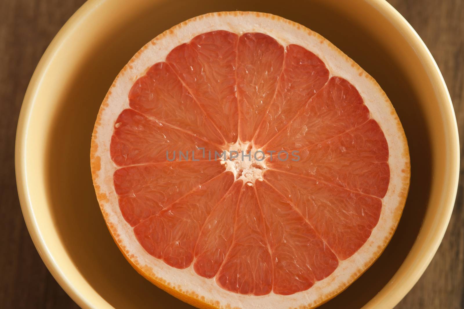 Fresh pink grapefruit half served in a bowl for breakfast viewed from overhead in a healthy diet concept