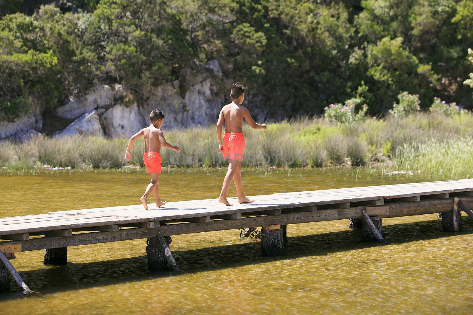 Boy walking on a wooden foot bridge on a lake