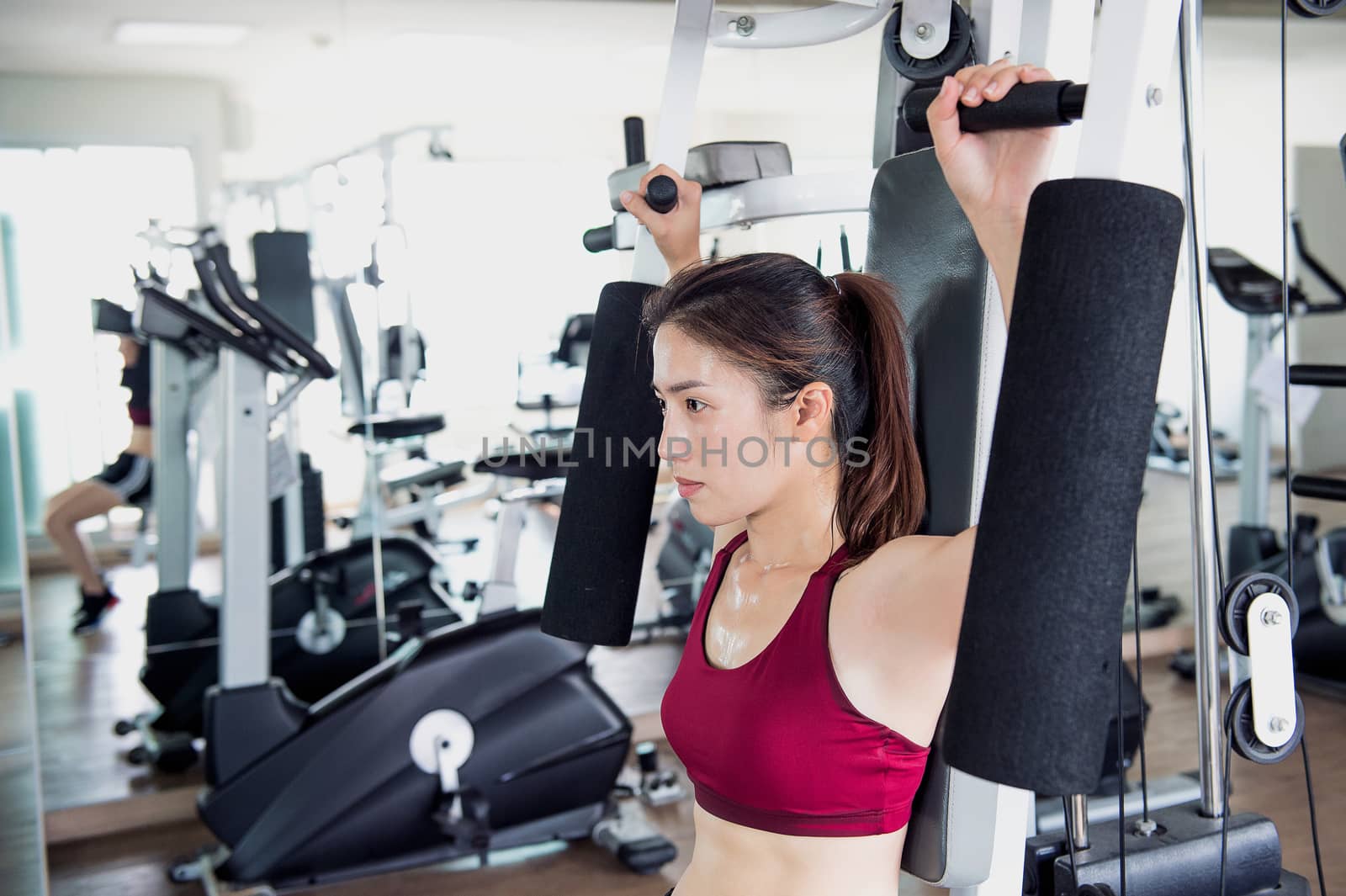 Young fitness woman executed exercise with exercise-machine in gym.