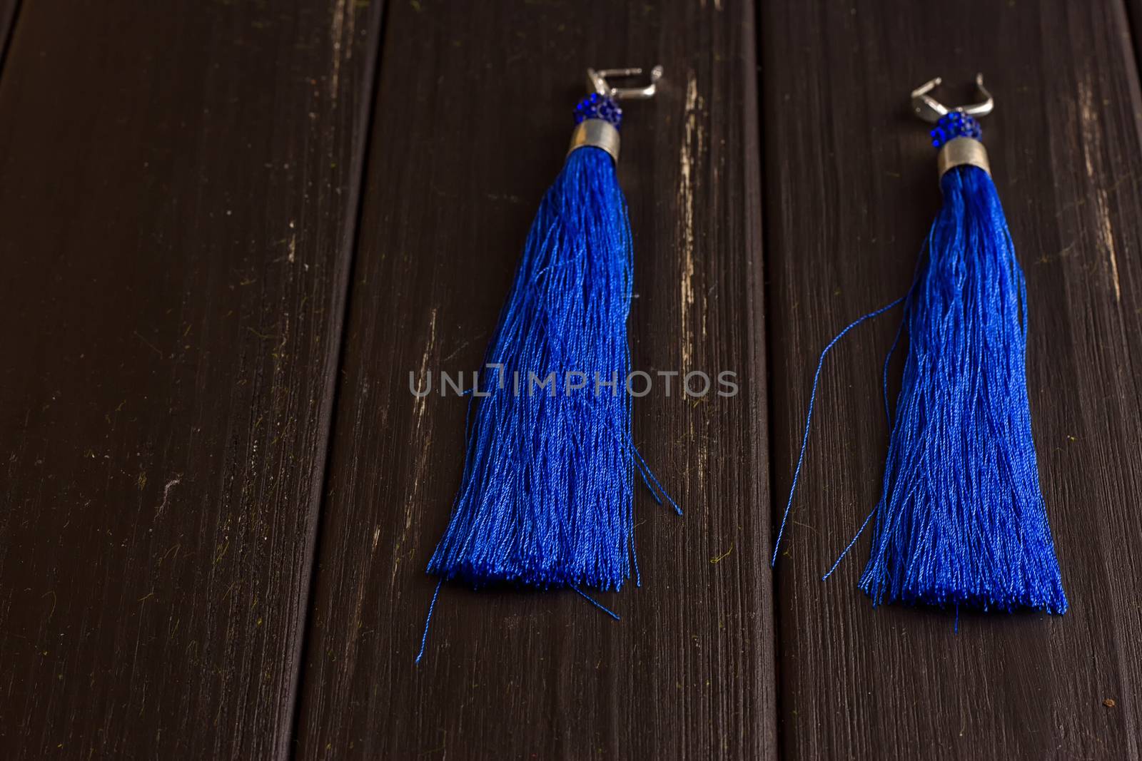 Blue thread earrings on a black wooden background