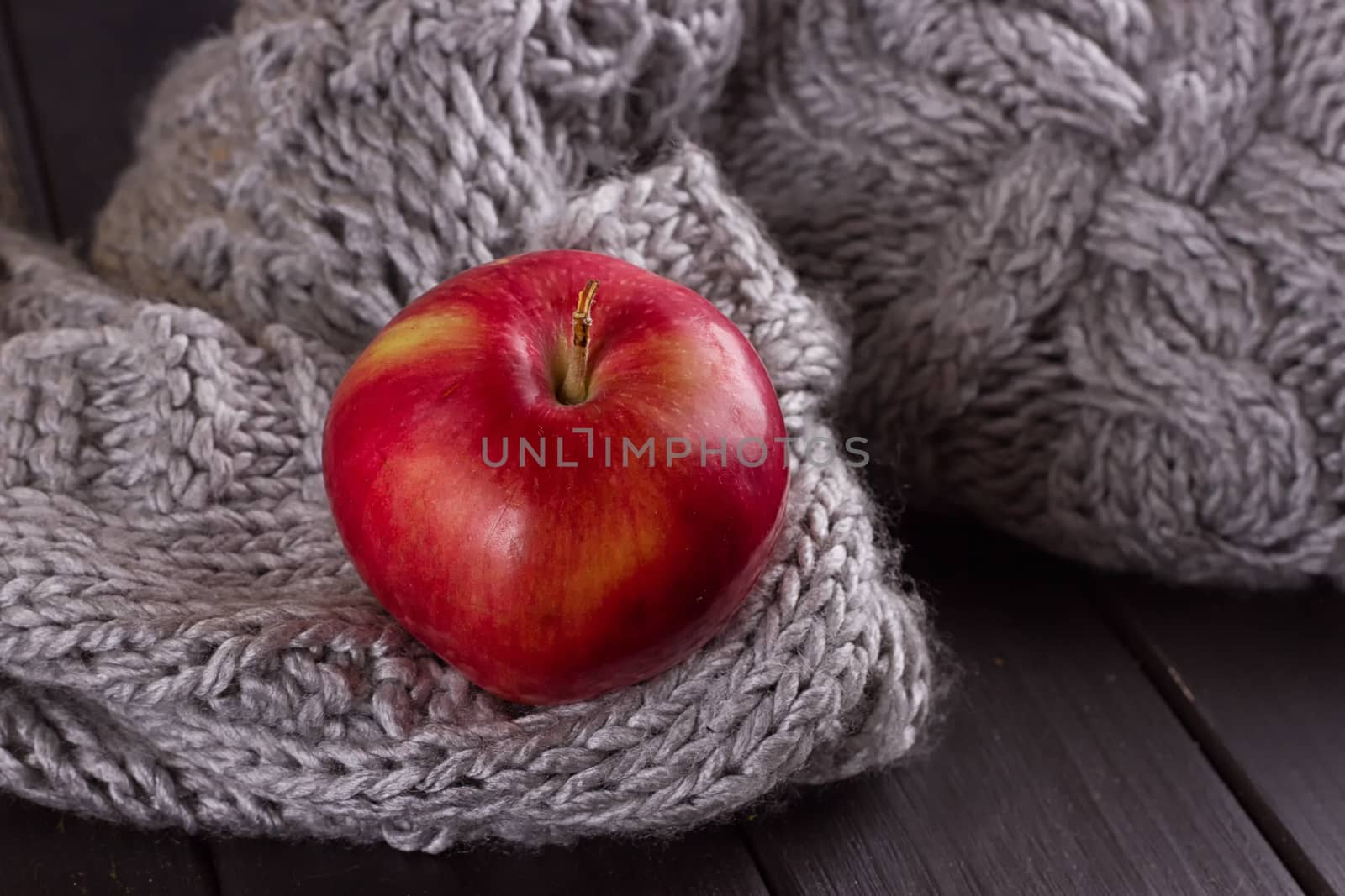 Red apple in a knitted gray sweater