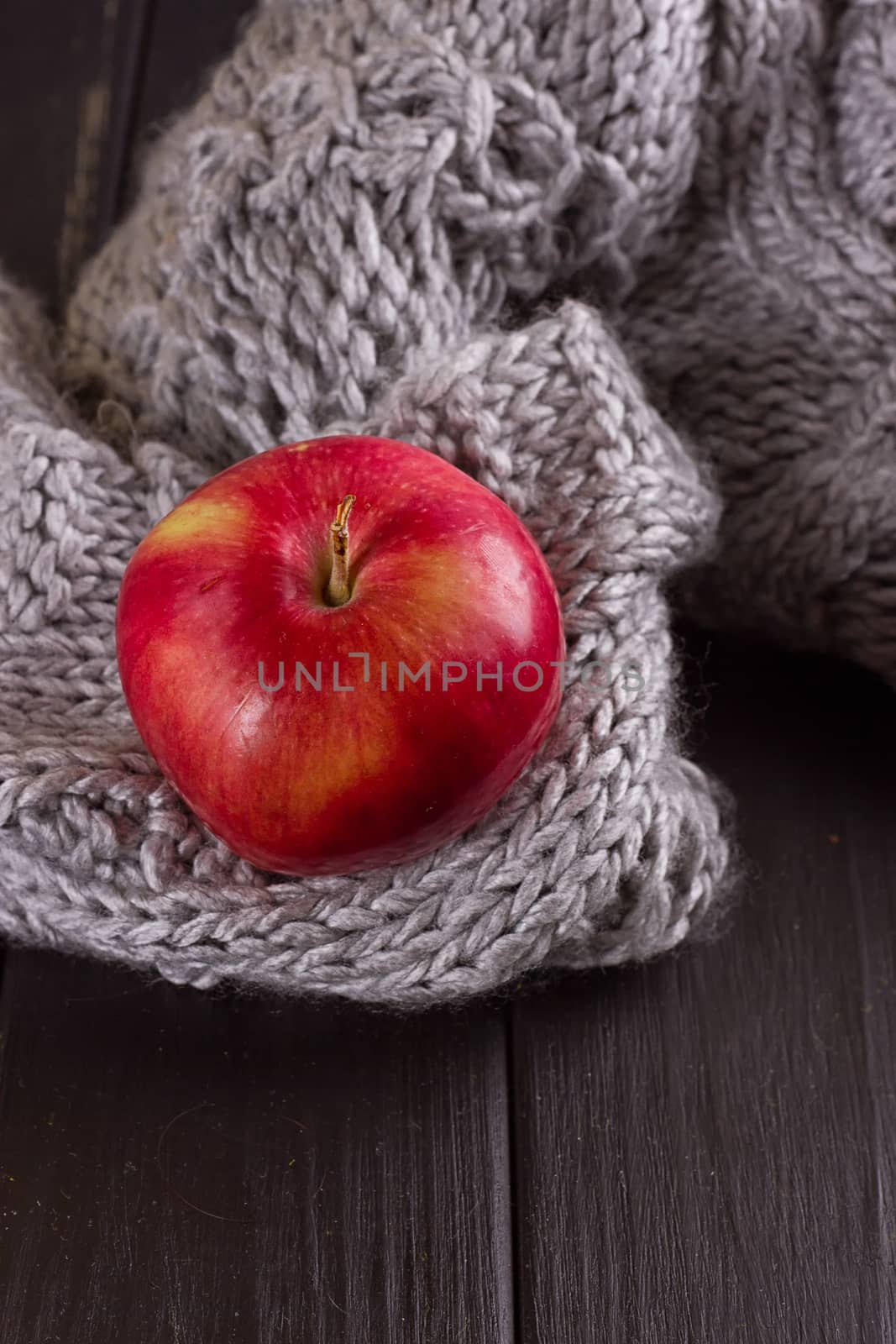 Red apple in a knitted gray sweater