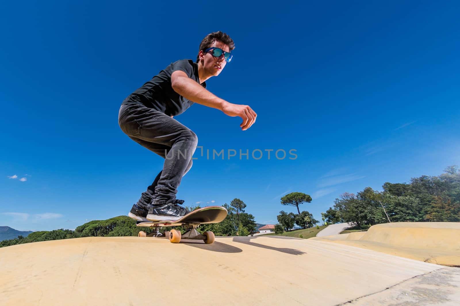 Skateboarder practice on a pump track park on a sunny summer day.