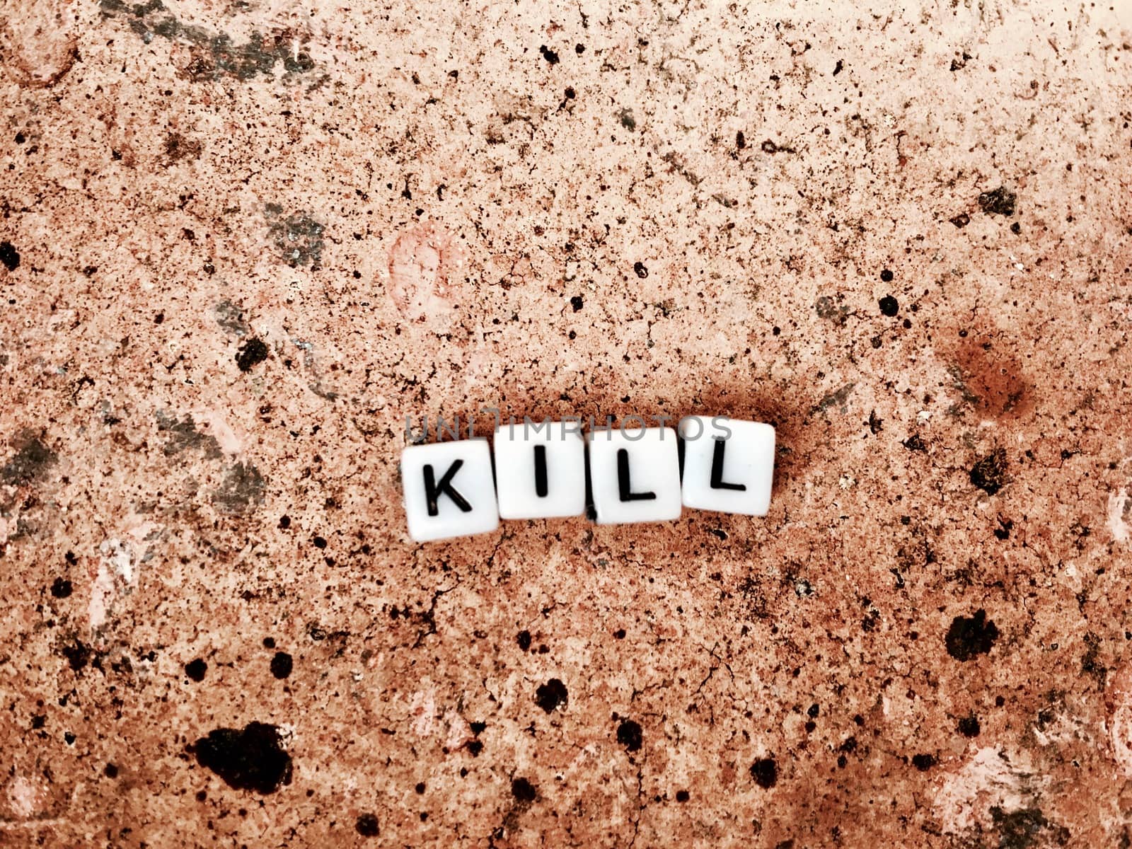 White inscription. Small white square letters. Kill on the brown brick.