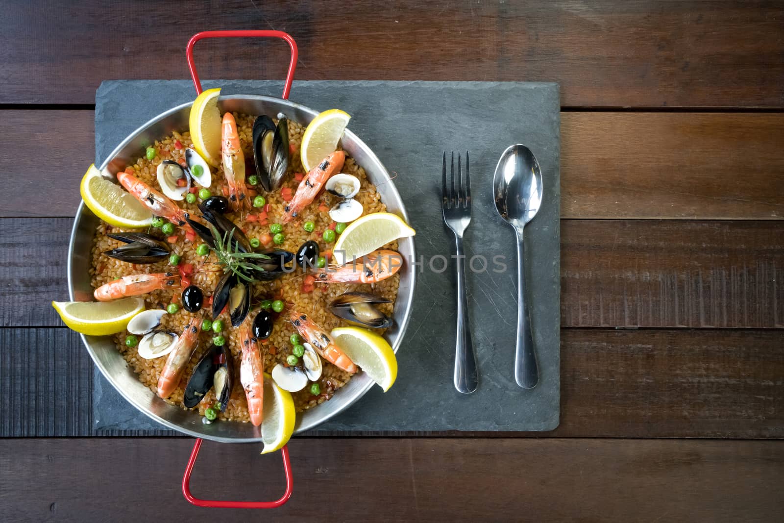 Paella with seafood vegetables and saffron served in the traditional pan top view.