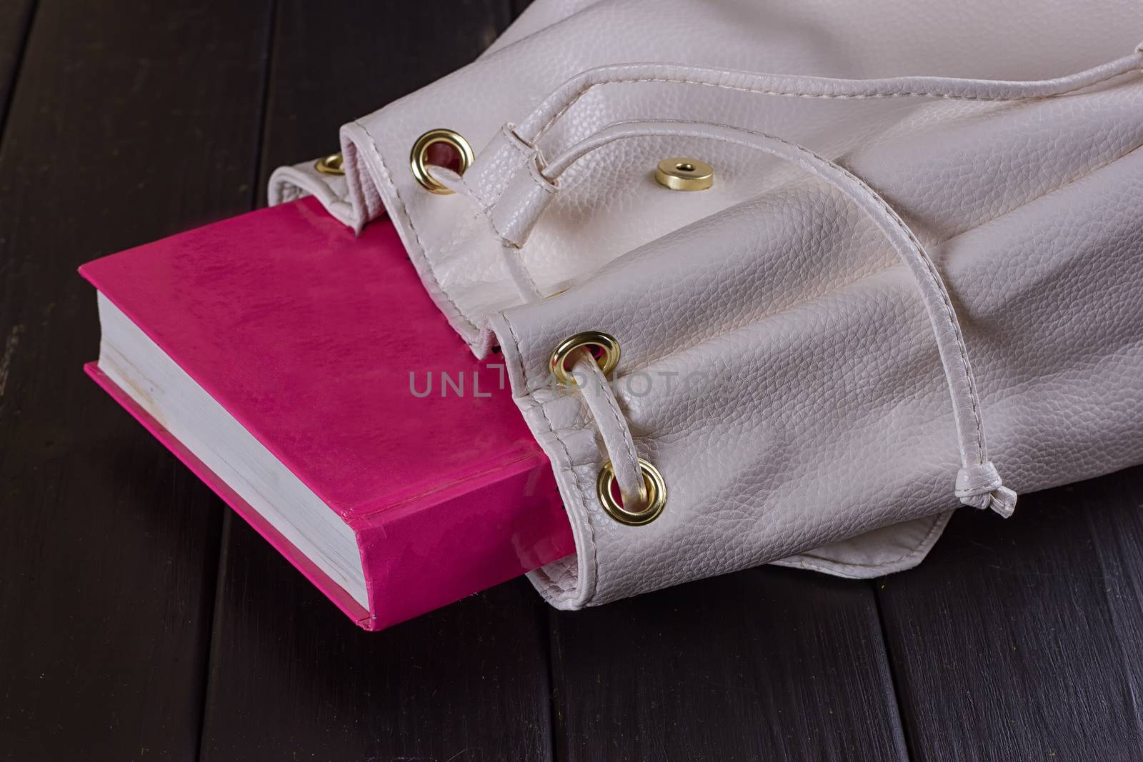 Book in female backpack closeup on the black background