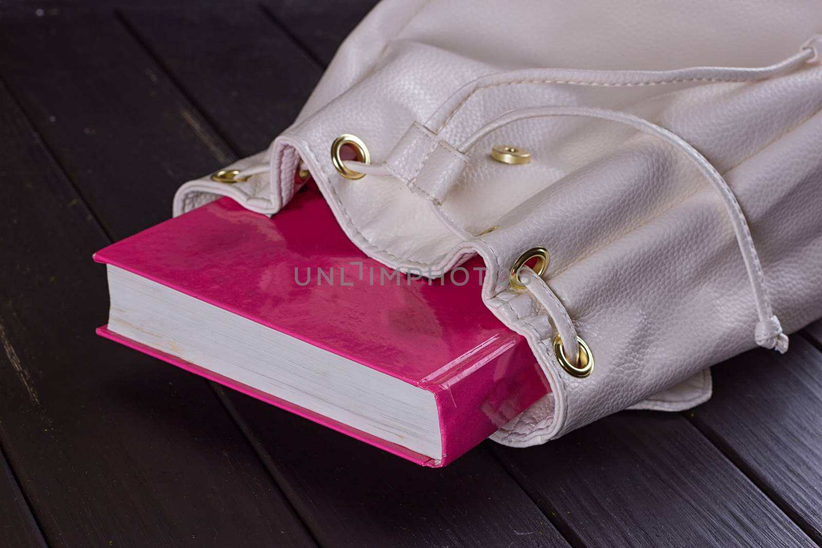 Book in female backpack closeup on the black background