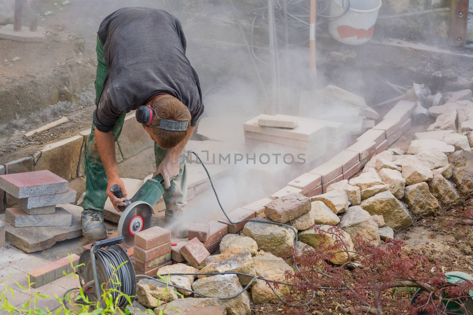 Man cutting stone slabs, concrete slab with an electric grinder