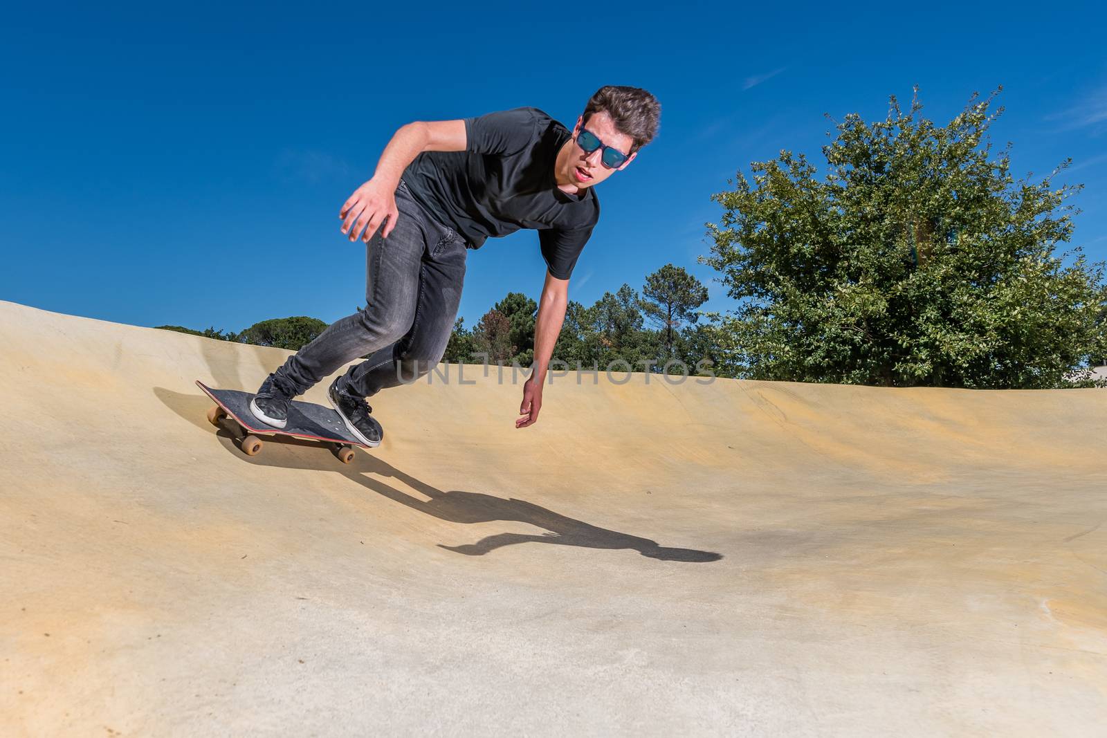 Skateboarder practice on a pump track park on a sunny summer day.