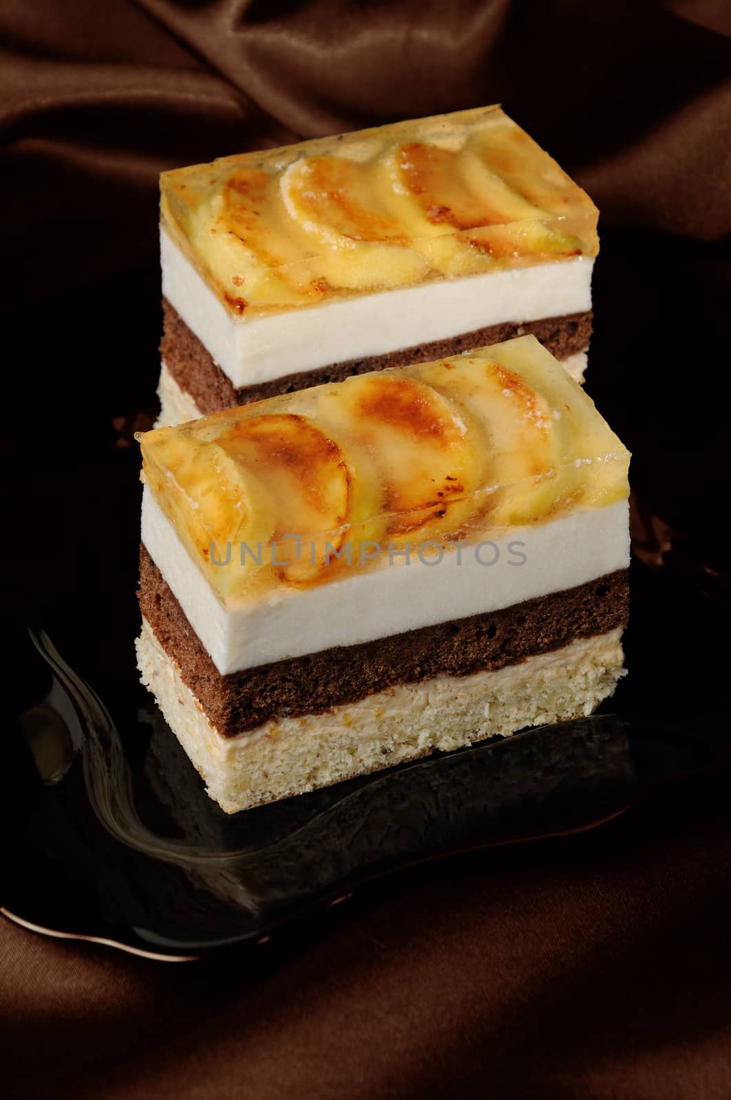 Cake stacked from caramel, apple mousse, chocolate and almond biscuit with a jelly layer of slices caramelized apple