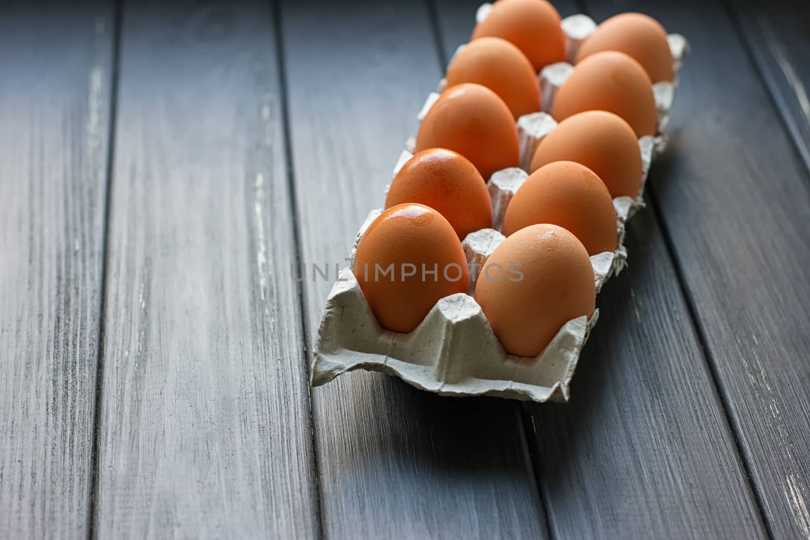 Cardboard egg box on black wooden background. Eggs container