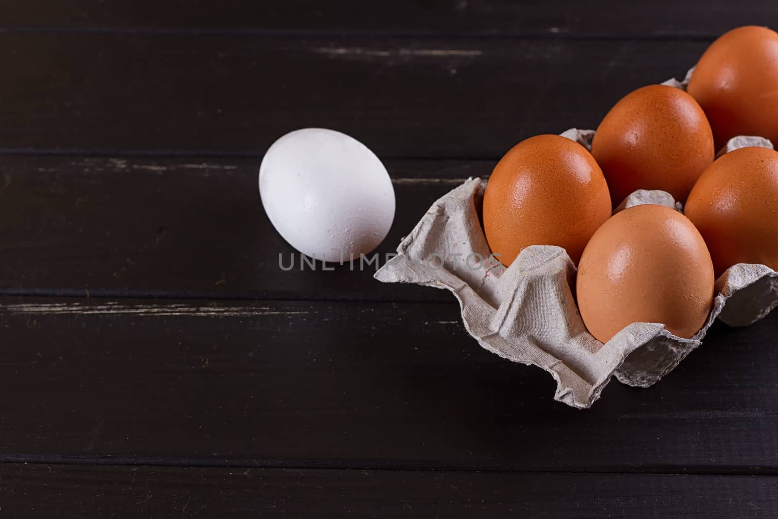 Cardboard egg box on black wooden background. Eggs container