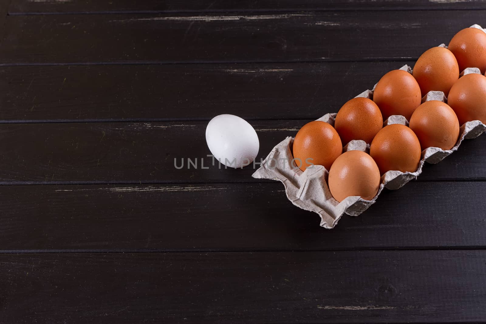 Cardboard egg box on black wooden background. Eggs container