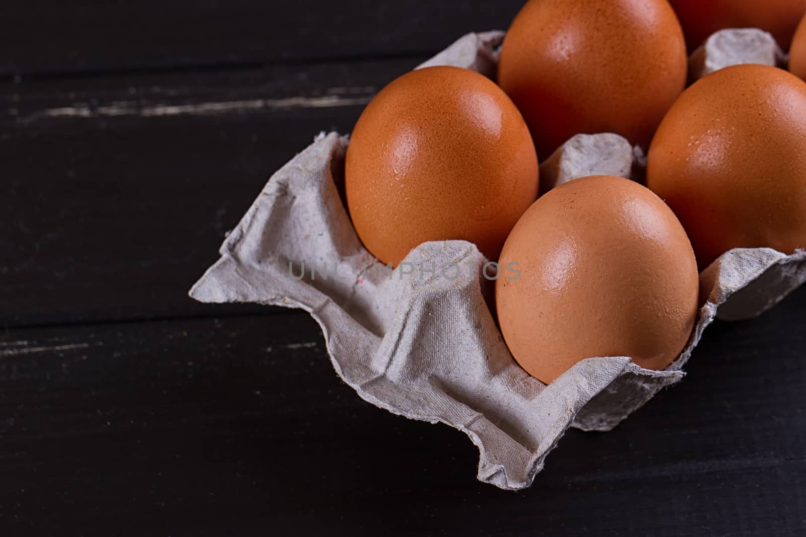 Cardboard egg box on black wooden background. Eggs container