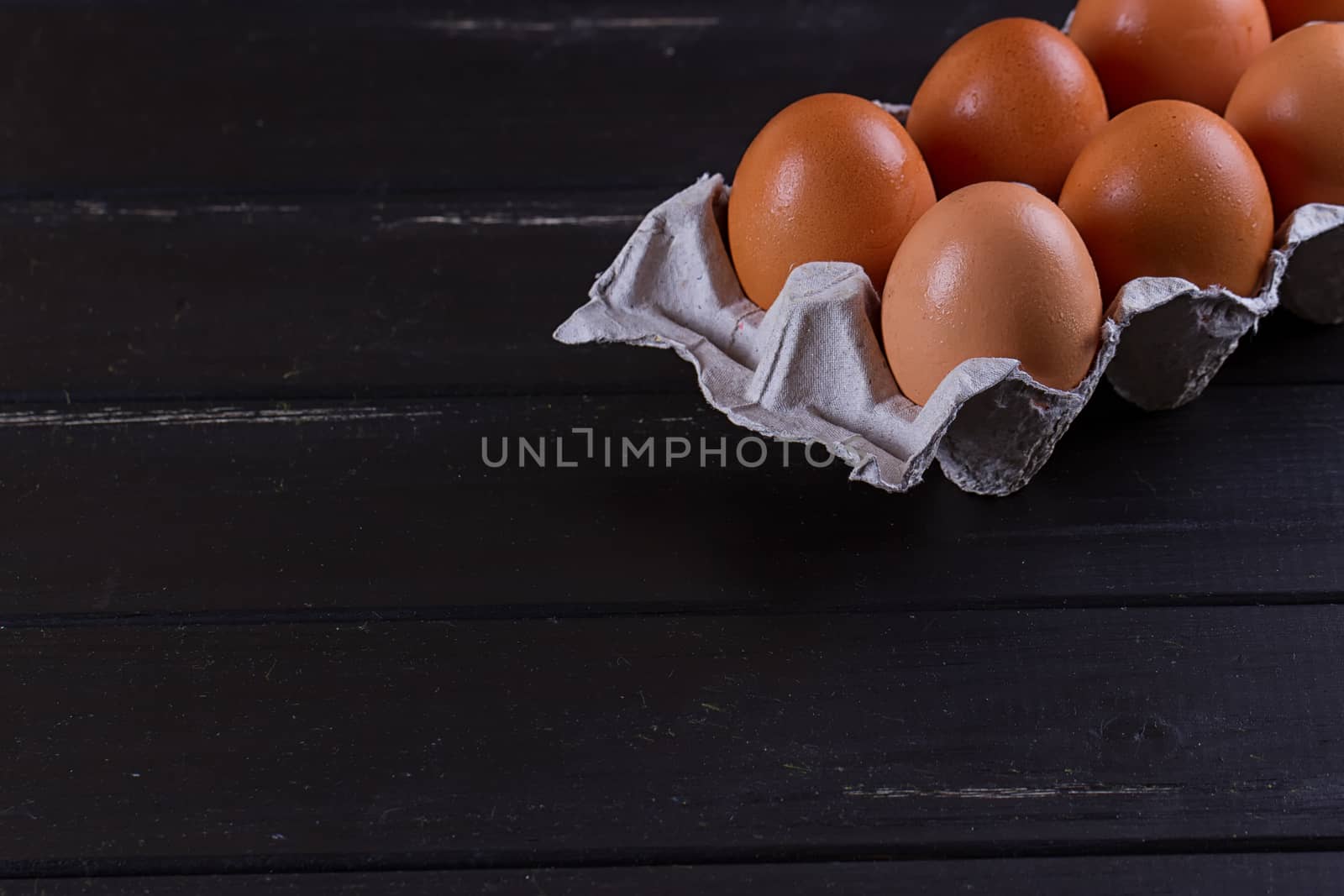 Cardboard egg box on black wooden background. Eggs container