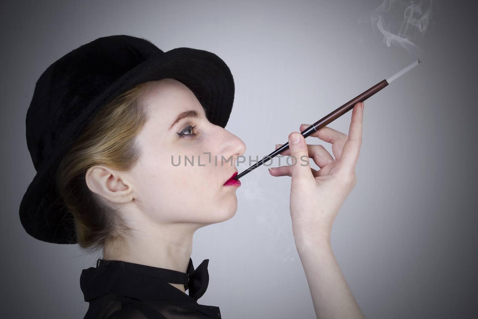 Young blond woman in a hat smokes through a mouthpiece