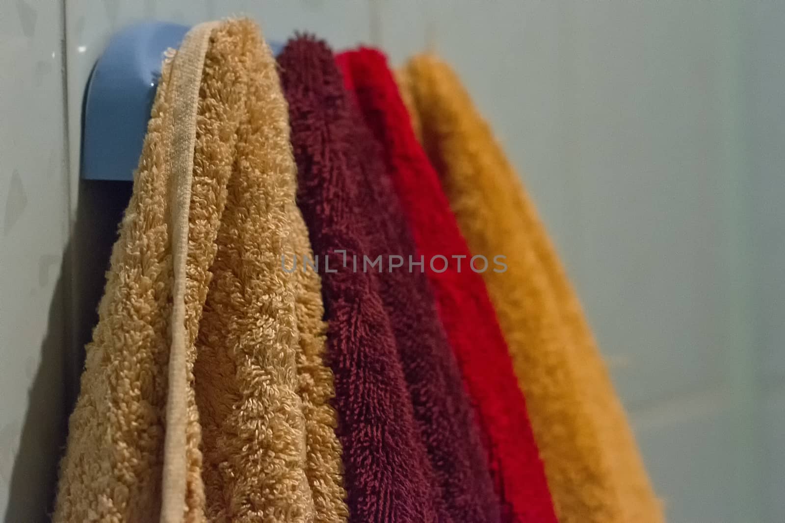 Multicolored towels hang on the hook in the bathroom home