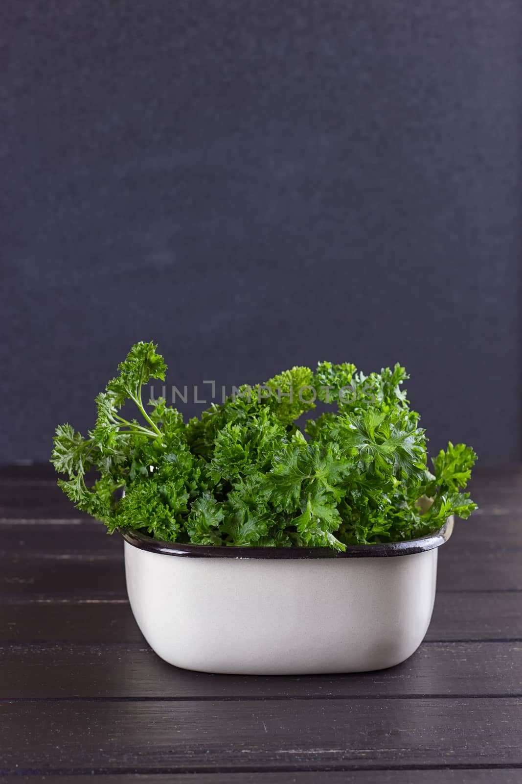 A bunch of fresh parsley in a ceramic tray on a black background. by victosha