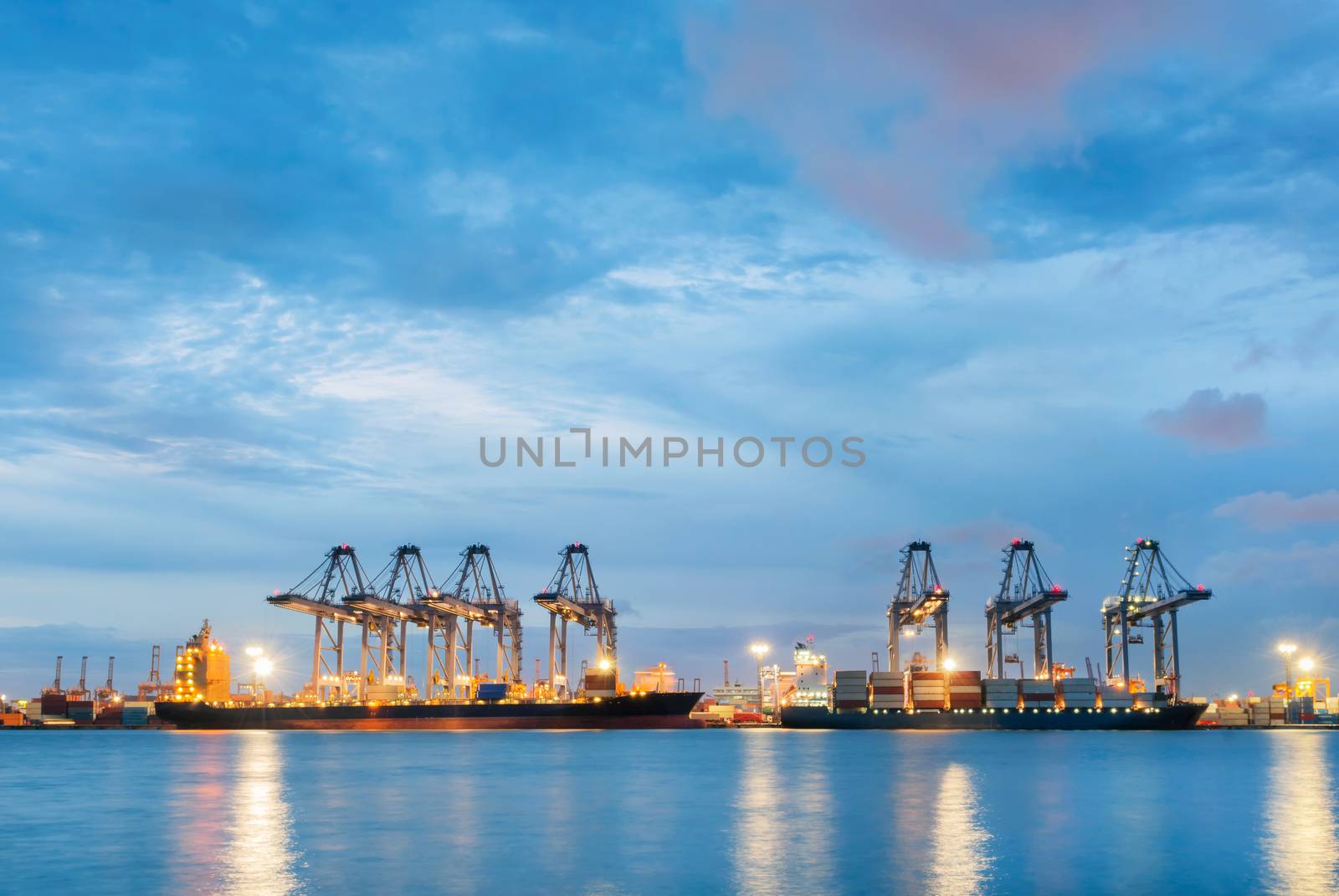 Container Cargo freight ship with working crane bridge in shipyard at dusk for Logistic Import Export background by Aunging