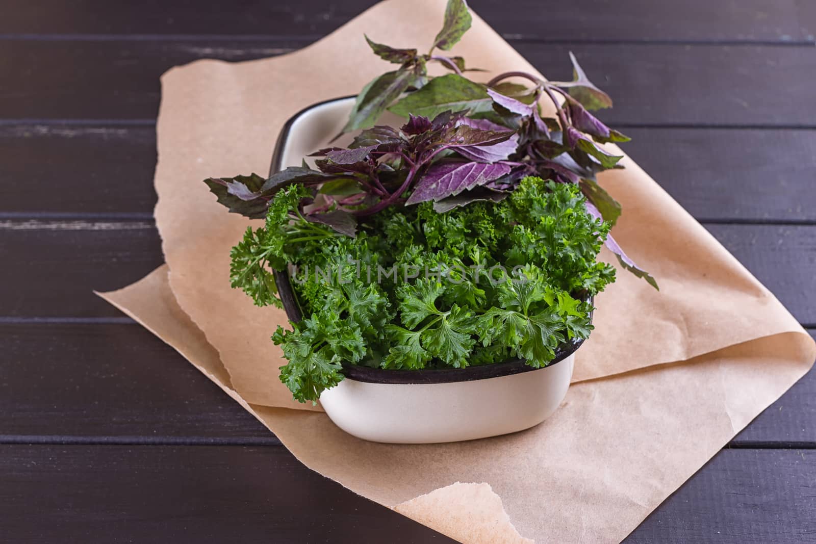 A bunch of fresh parsley in a ceramic tray on a black background. Fresh greens for salad