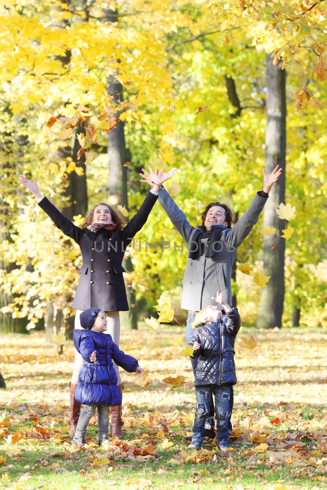 Happy family playing with autumn leaves by ALotOfPeople