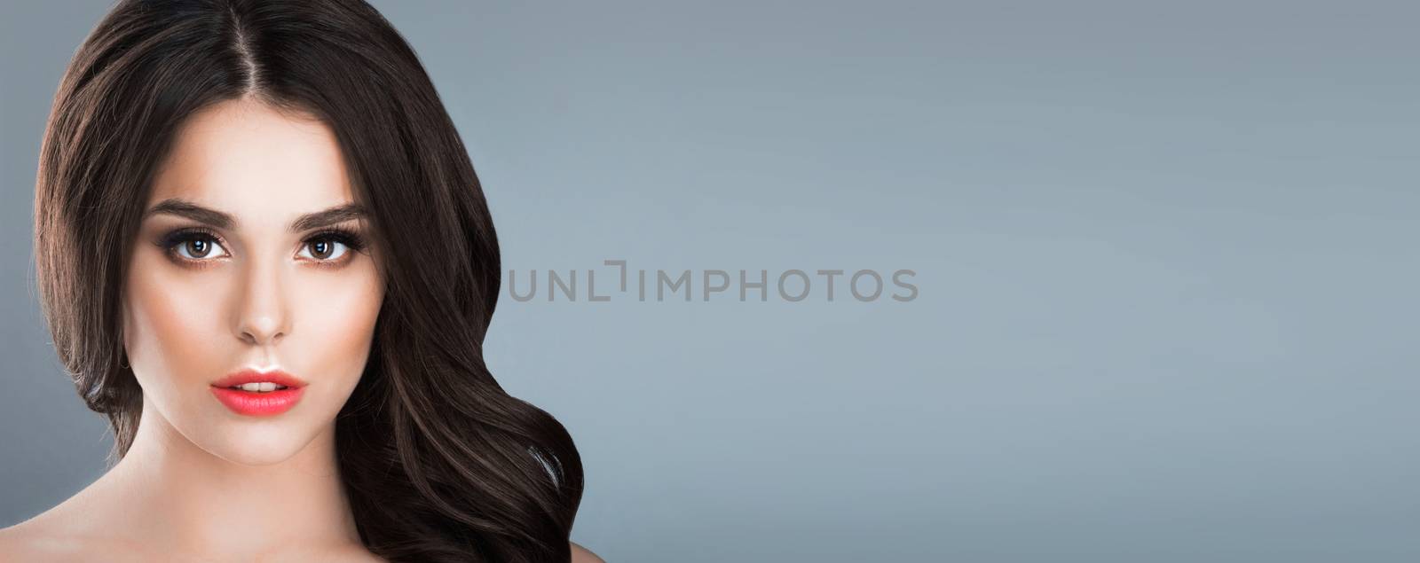 Beauty studio portrait of brunette woman with natural make-up over gray background