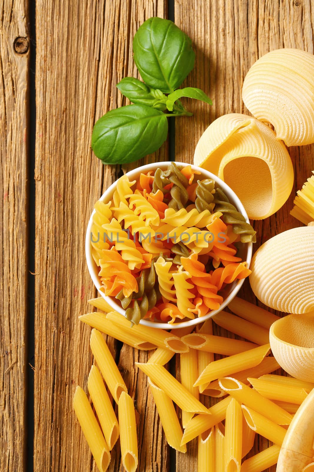 Various types of dried pasta on wooden background