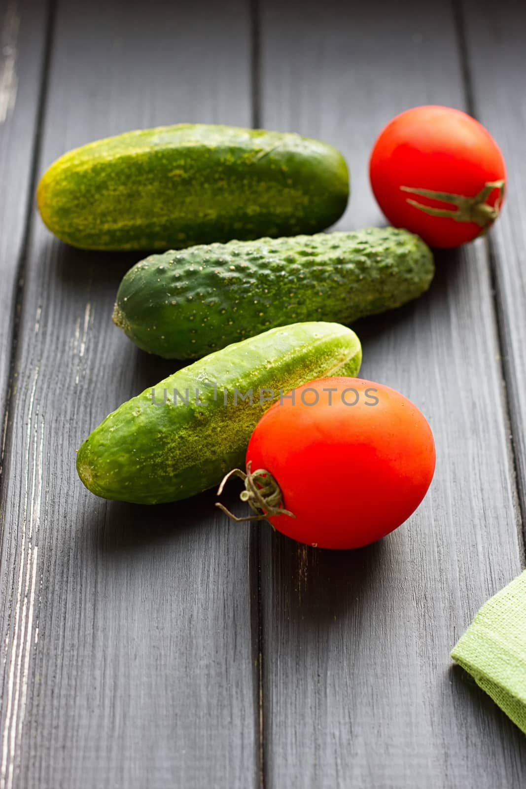 Tomatoes and cucumber on the black wood background