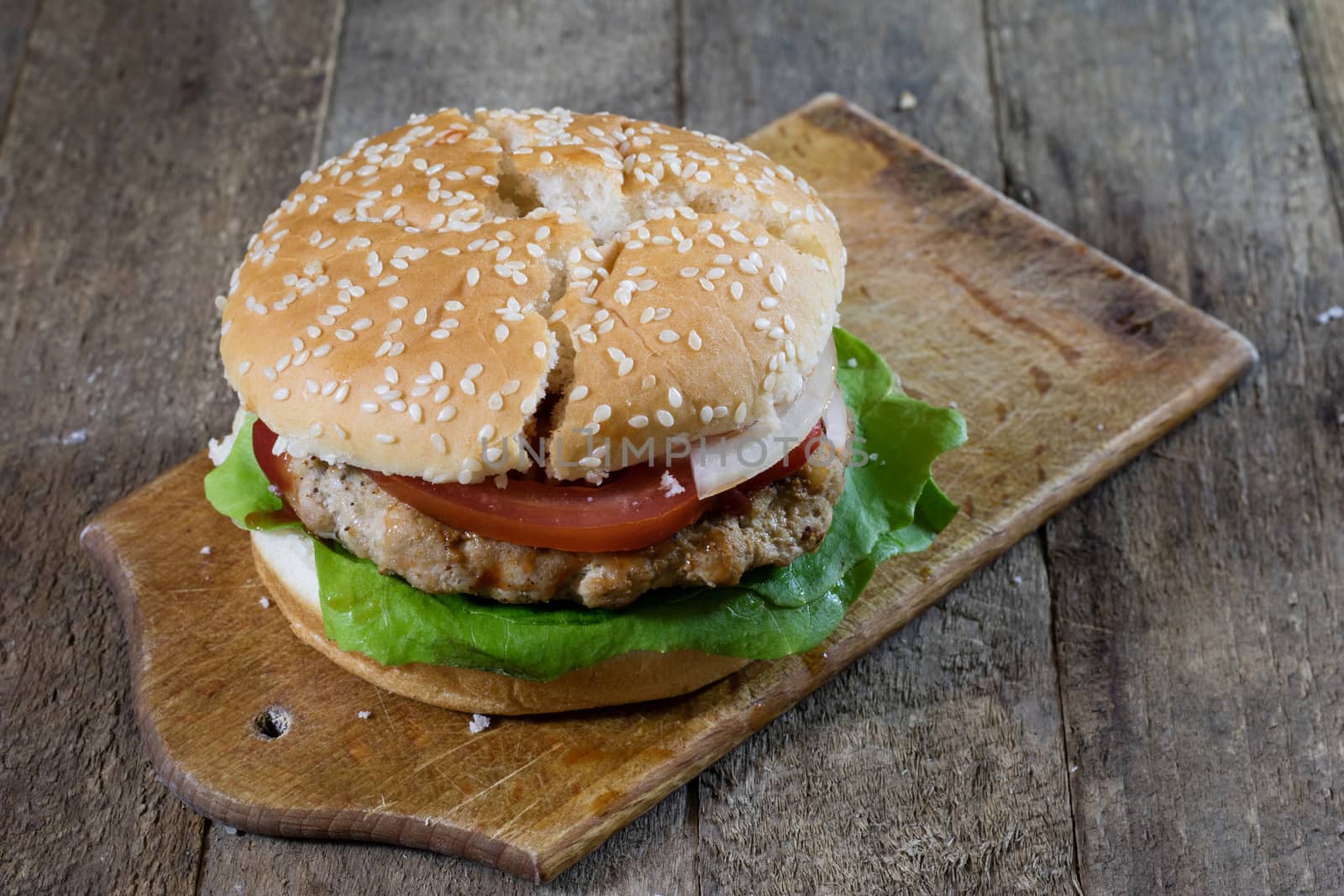 Roll with roast cutlet. Hamburger on a wooden board. Kitchen table, black background.