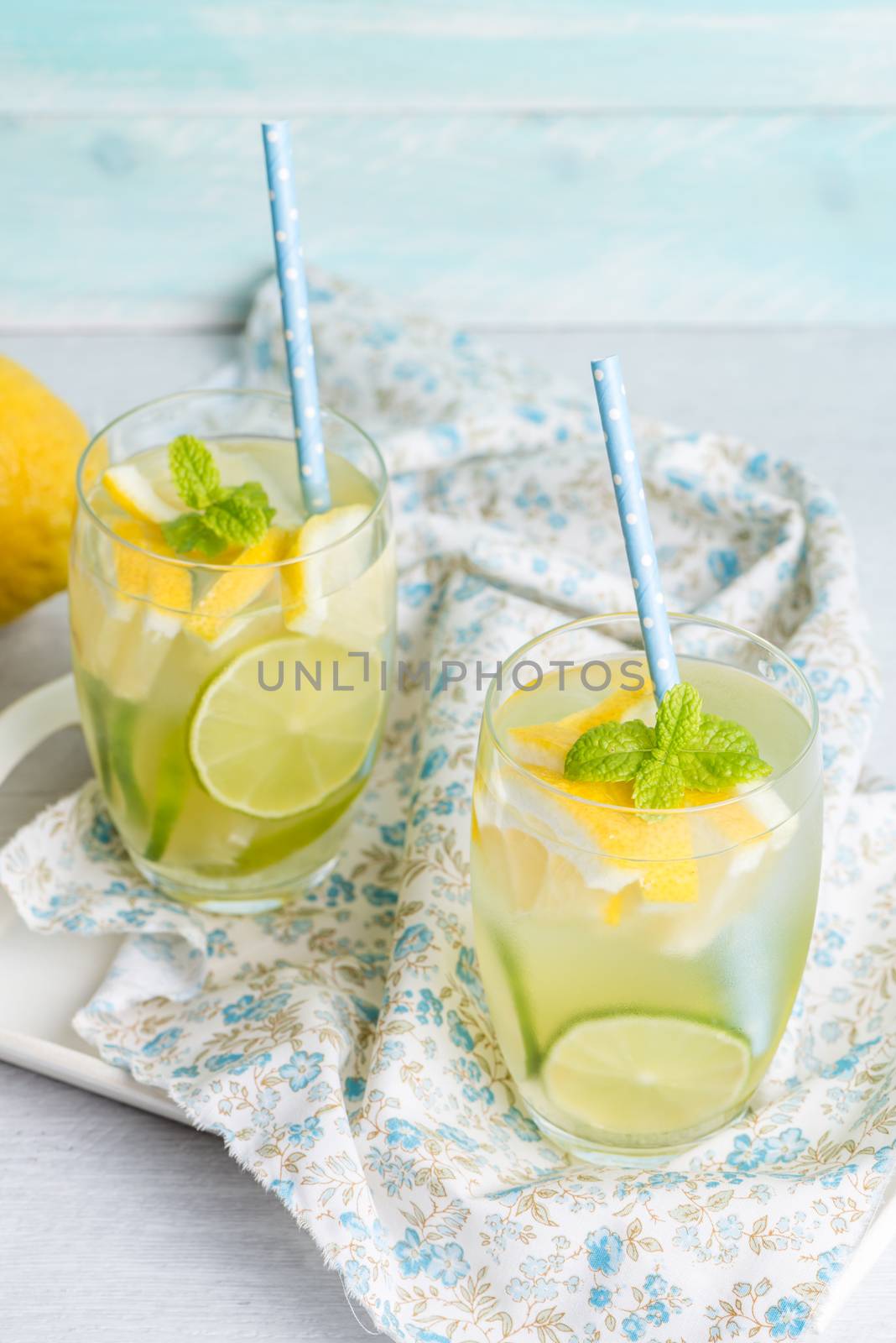 Summer citrus fruits drink on wooden background. Detox citrus infused flavored water. Refreshing summer homemade cocktail with lemon. Fresh lemon and lemonade on wooden background