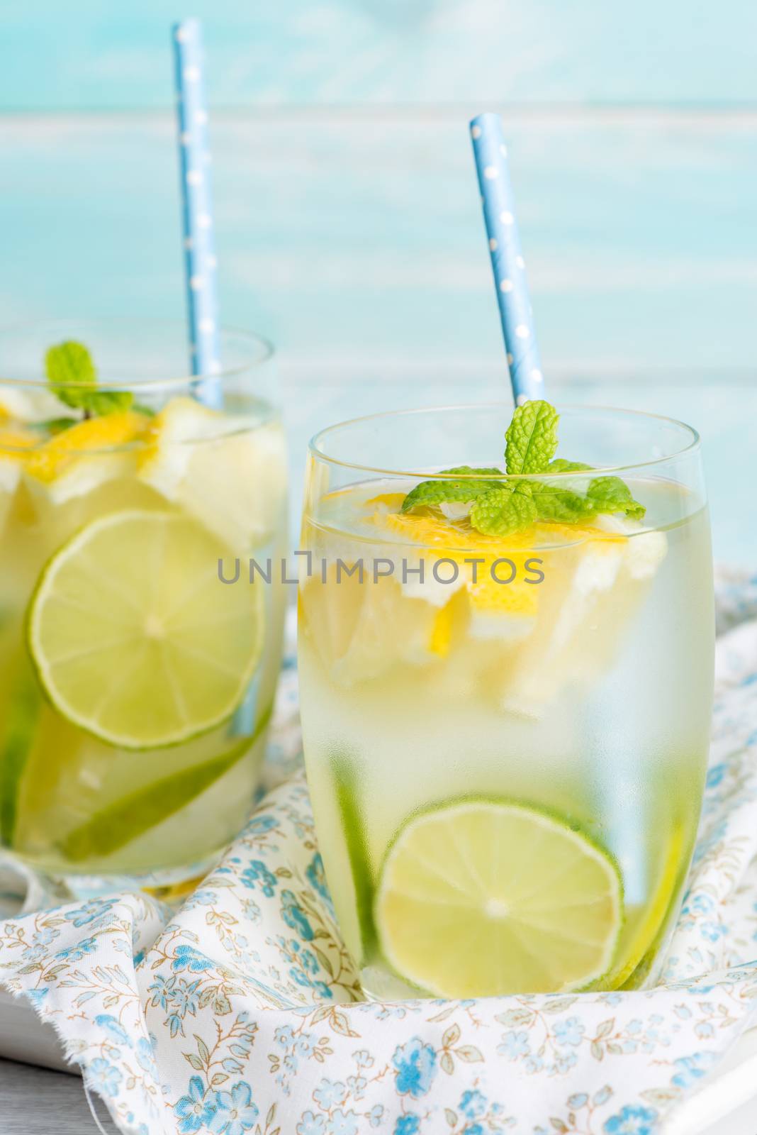 Summer citrus fruits drink on wooden background. Detox citrus infused flavored water. Refreshing summer homemade cocktail with lemon. Fresh lemon and lemonade on wooden background